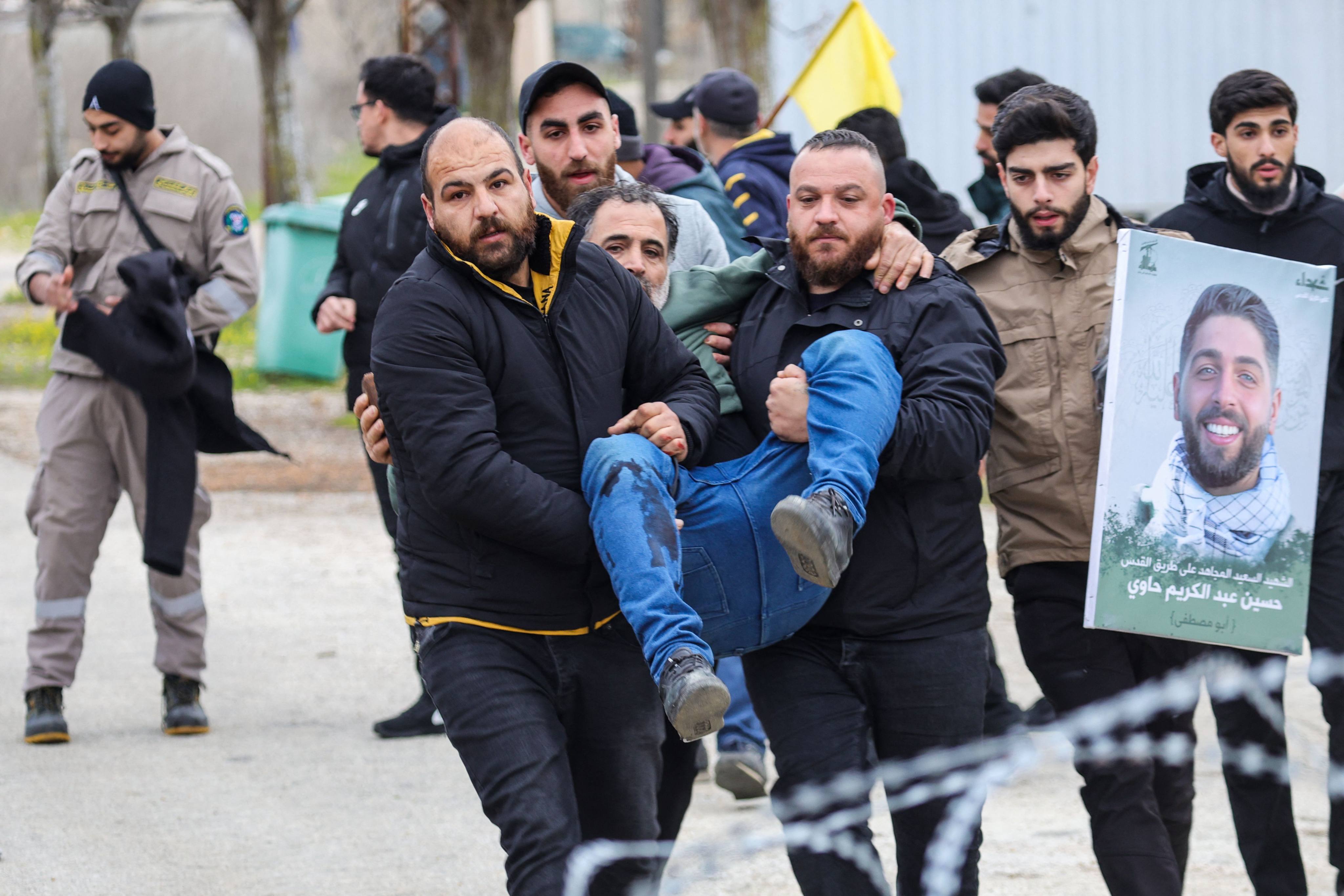 Residents carry a man injured by Israeli fire to safety in Borj El Mlouk, in the outskirts of Kfar Kila, on January 26. Israeli troops fired at residents of south Lebanon on January 26, killing two and wounding 32, health officials said, as hundreds of people tried to return to their homes on the deadline for Israeli forces to withdraw from the area. Photo: AFP