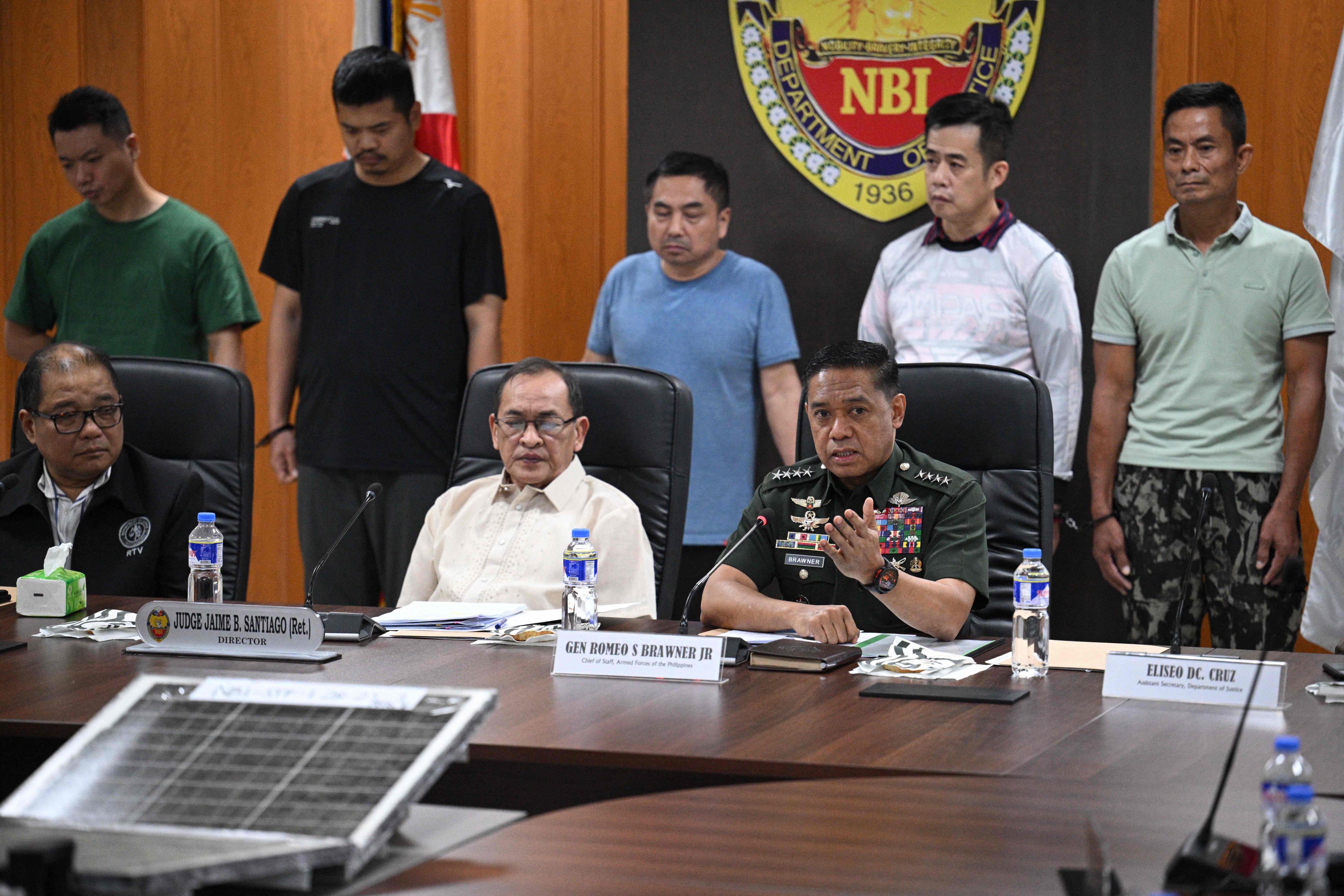 Philippine military chief General Romeo Brawner (front right) speaks alongside National Bureau of Investigation chief Jaime Santiago (front centre) and undersecretary of the Department of Justice Raul Vasquez (front left) during the presentation of five arrested alleged Chinese spies (back row) in Manila on Wednesday. Photo: AFP