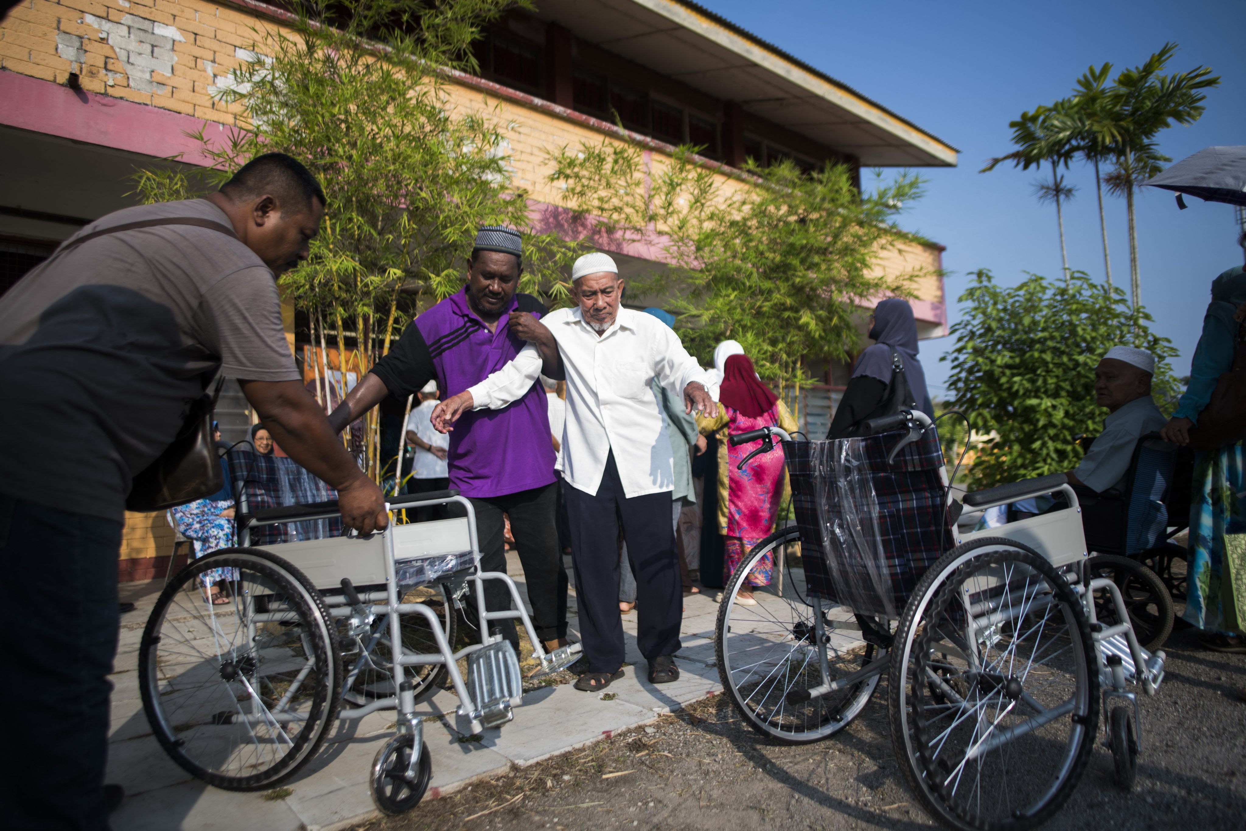 An elderly man is helped into a wheelchair in Alor Setar, Kedah, Malaysia. Photo: AFP