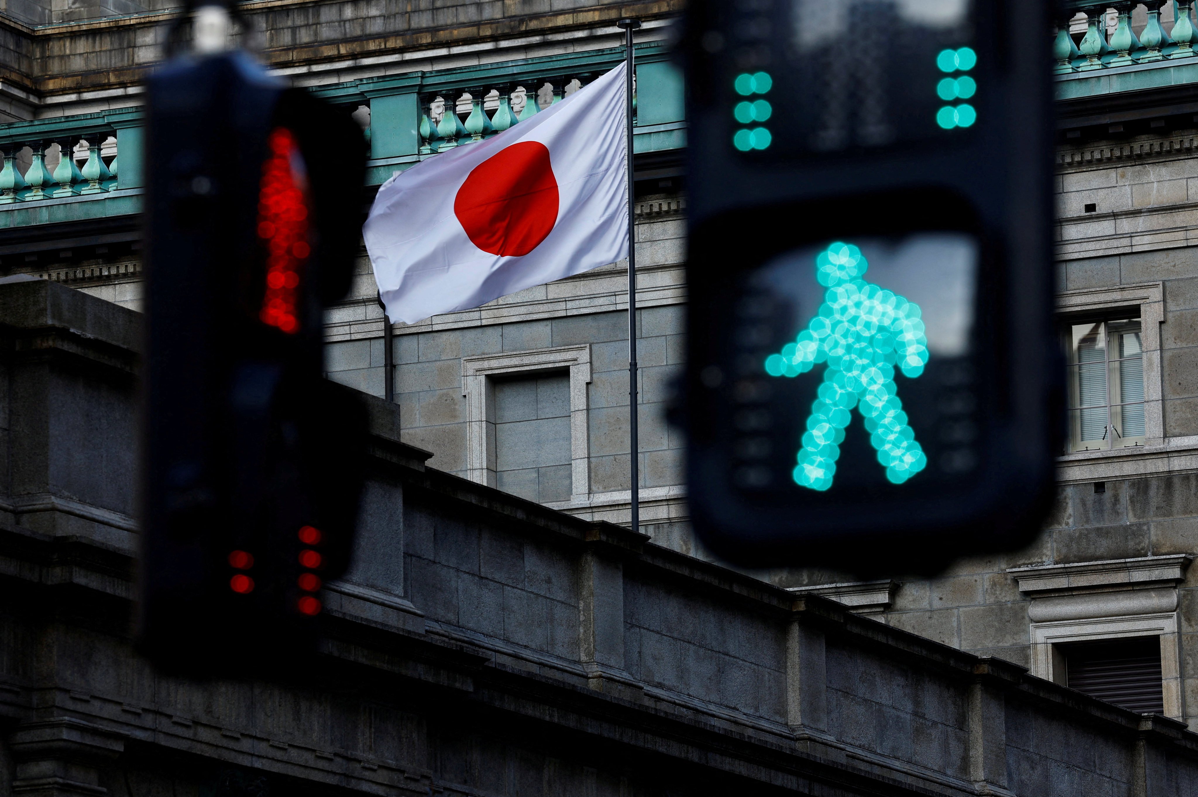 FILE PHOTO: Japanese national flag hoisted atop of the Bank of Japan headquarters building is seen between traffic signals in Tokyo, Japan January 23, 2025.  REUTERS/Issei Kato/File Photo