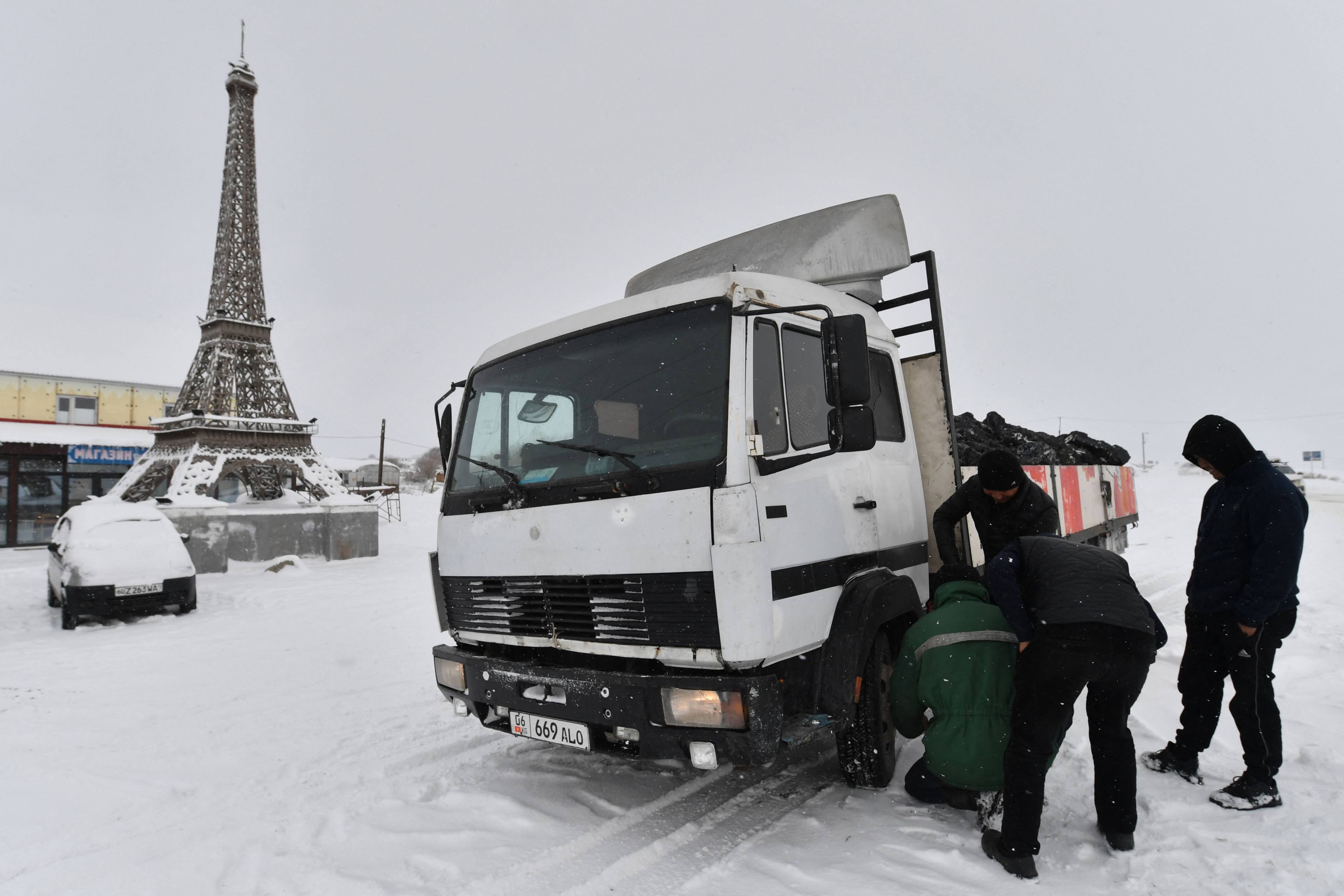 Men repair a truck next to a replica of the Eiffel Tower in the village unofficially called Paris, in Kyrgyzstan, Central Asia. Photo: AFP