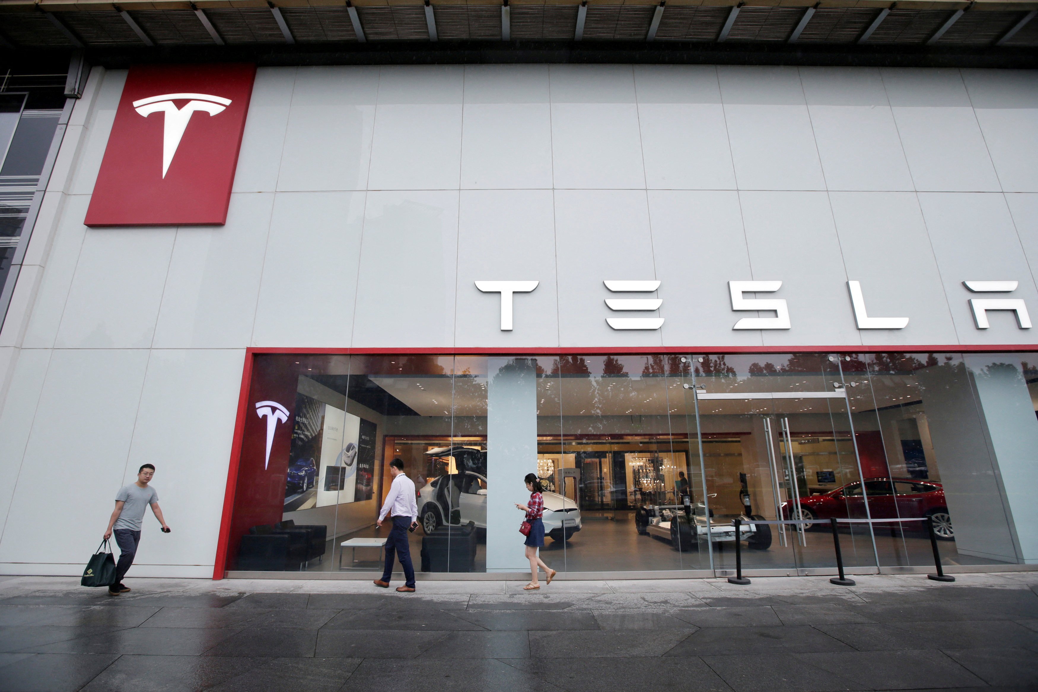 People walk past a showroom outside Tesla China’s headquarters in Beijing in July 2018. Photo: Reuters