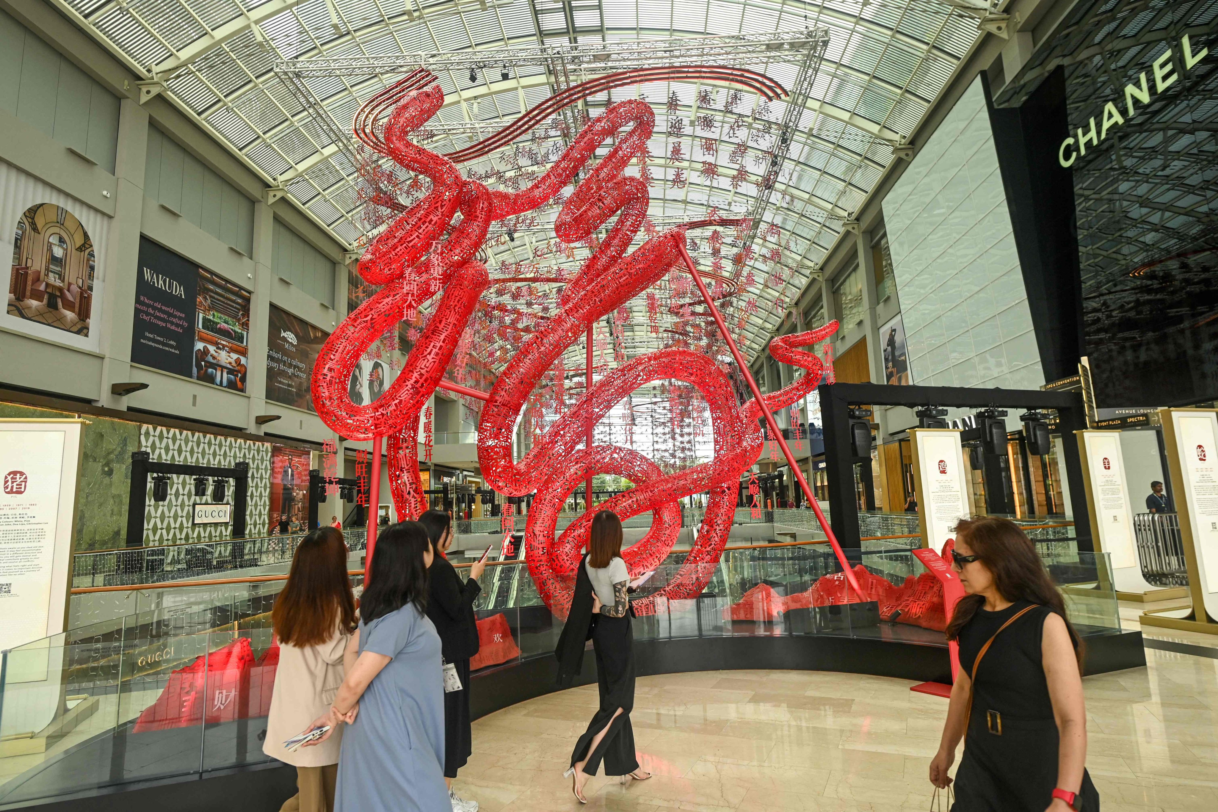 People walk past a display for the Lunar New Year of the Snake at the Marina Bay Sands shopping centre in Singapore. Photo: AFP