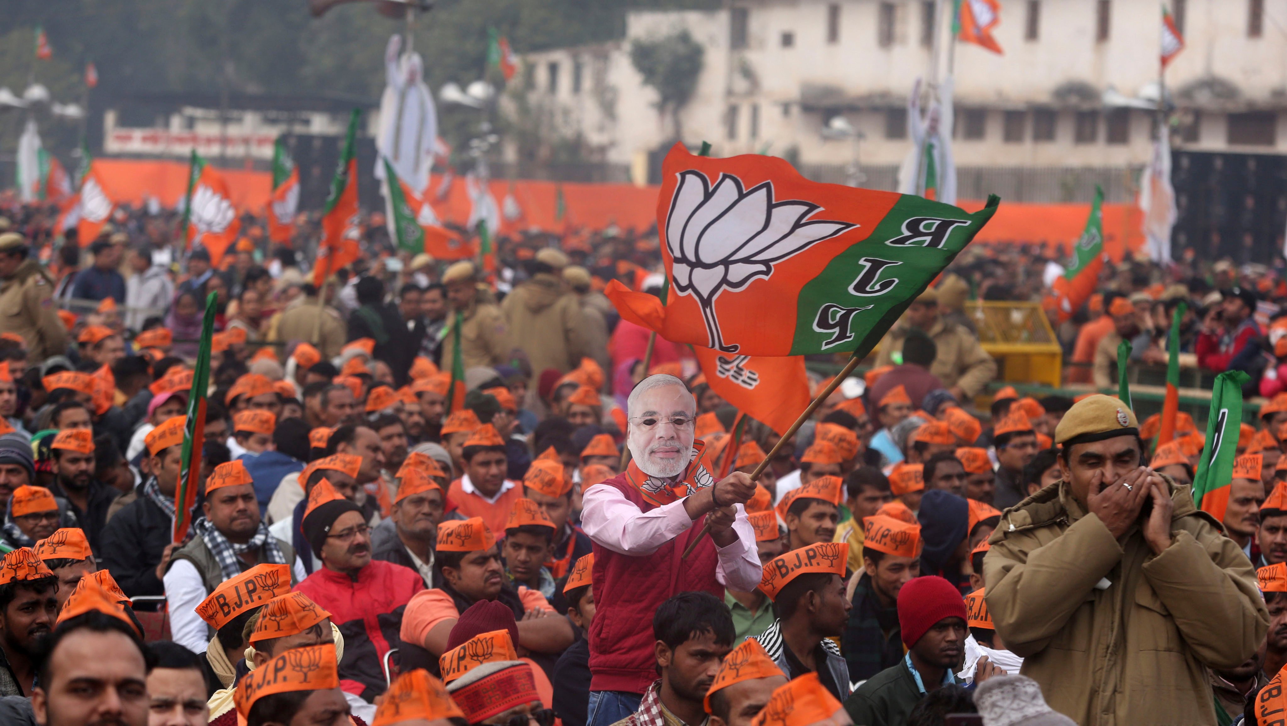 A man wearing a mask of Indian Prime Minister Narendra Modi waves a flag of his Hindu nationalist Bharatiya Janata Party during a rally in New Delhi, India. Photo: AP