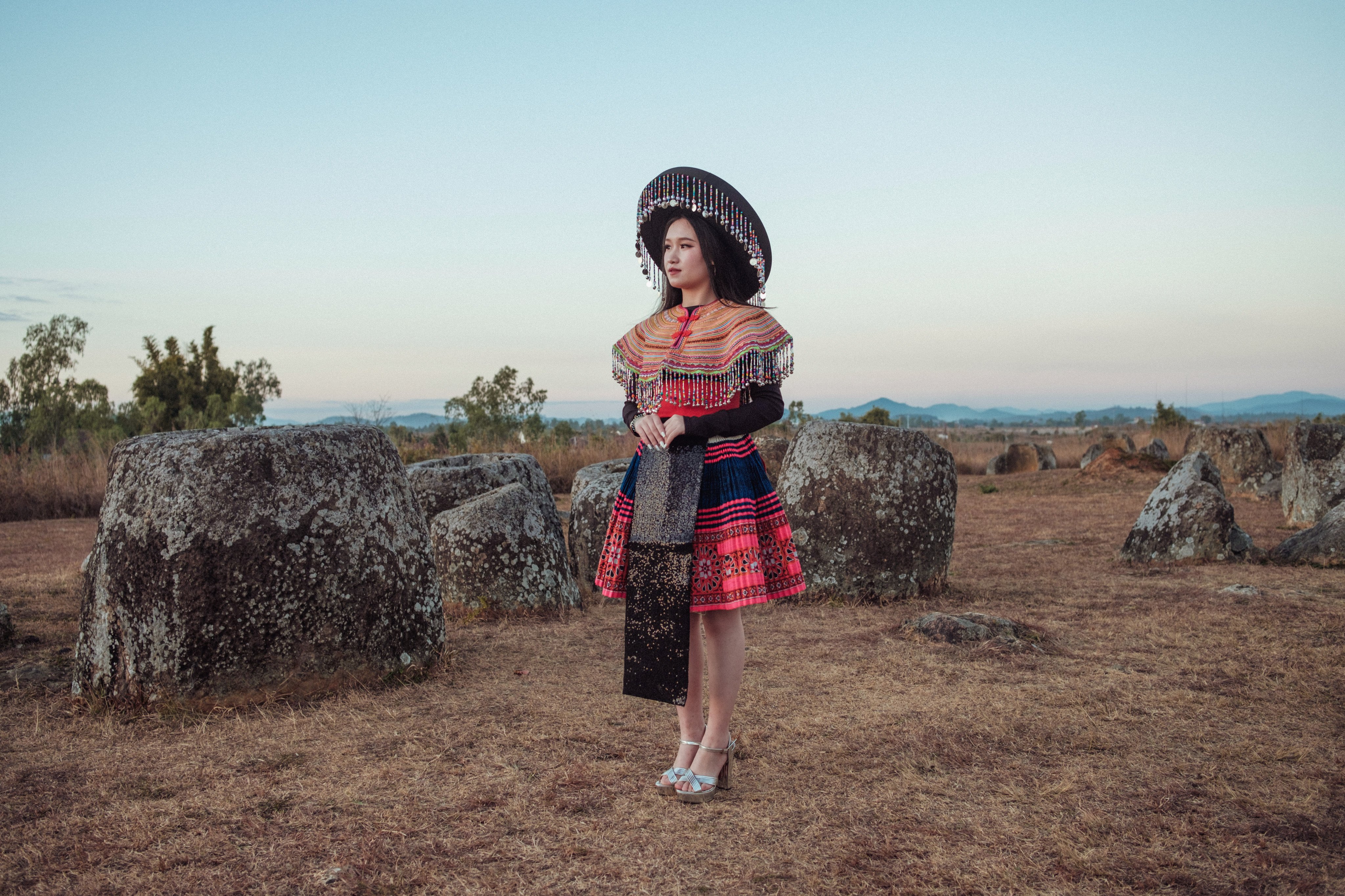 A Hmong woman stands among the ancient stones of the Plain of Jars (Site 1),
outside Phonsavan. The Hmong New Year celebration in Phonsavan, the largest of its kind in Laos, sees young Hmong men and women mix and match traditional attire with modern accessories. Photo: Nicolas Bosoni