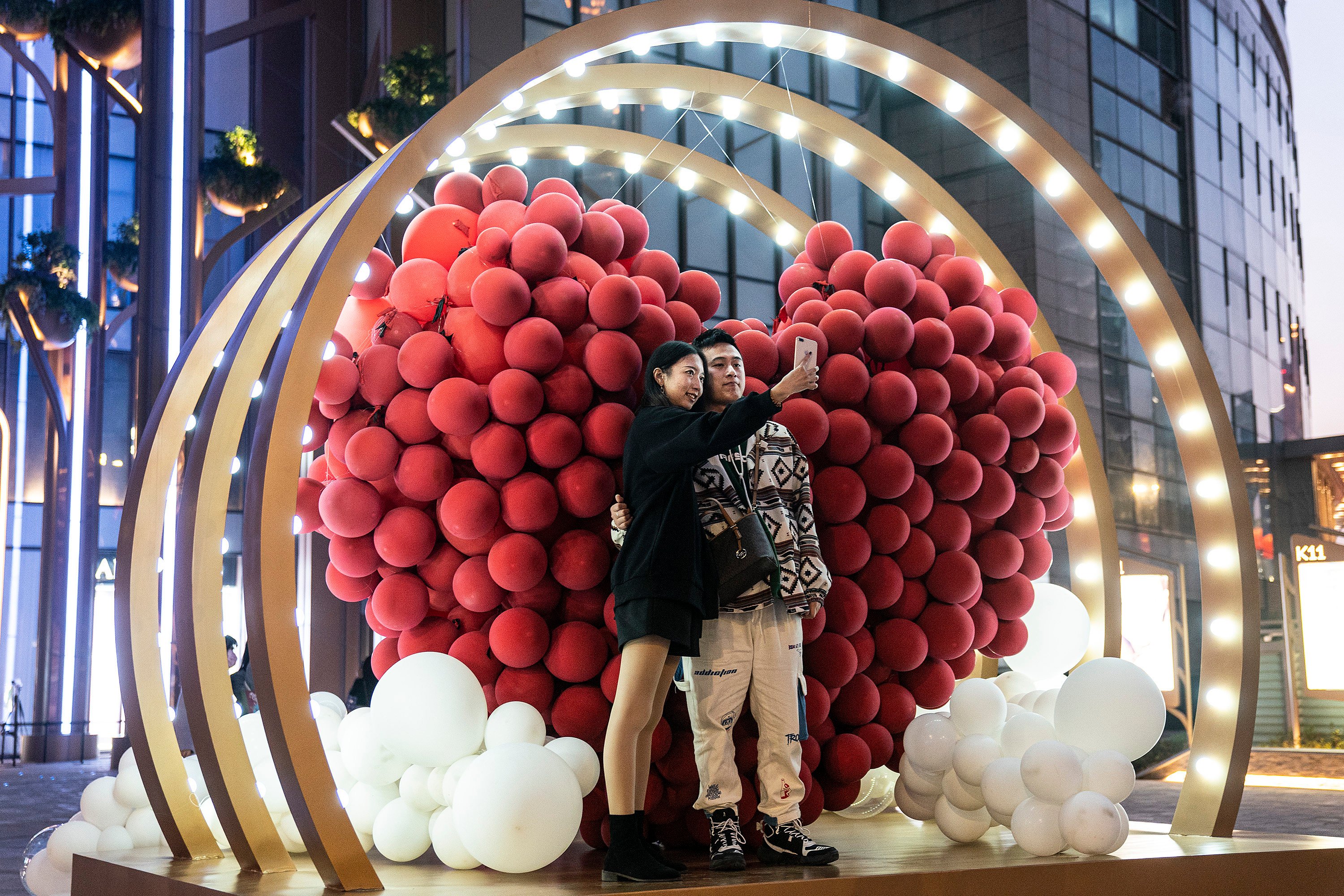 A  couple photograph themselves in front of balloons in a heart shape in a shopping mall in Wuhan, central China, on Valentine’s Day in 2021. Photo: Getty Images