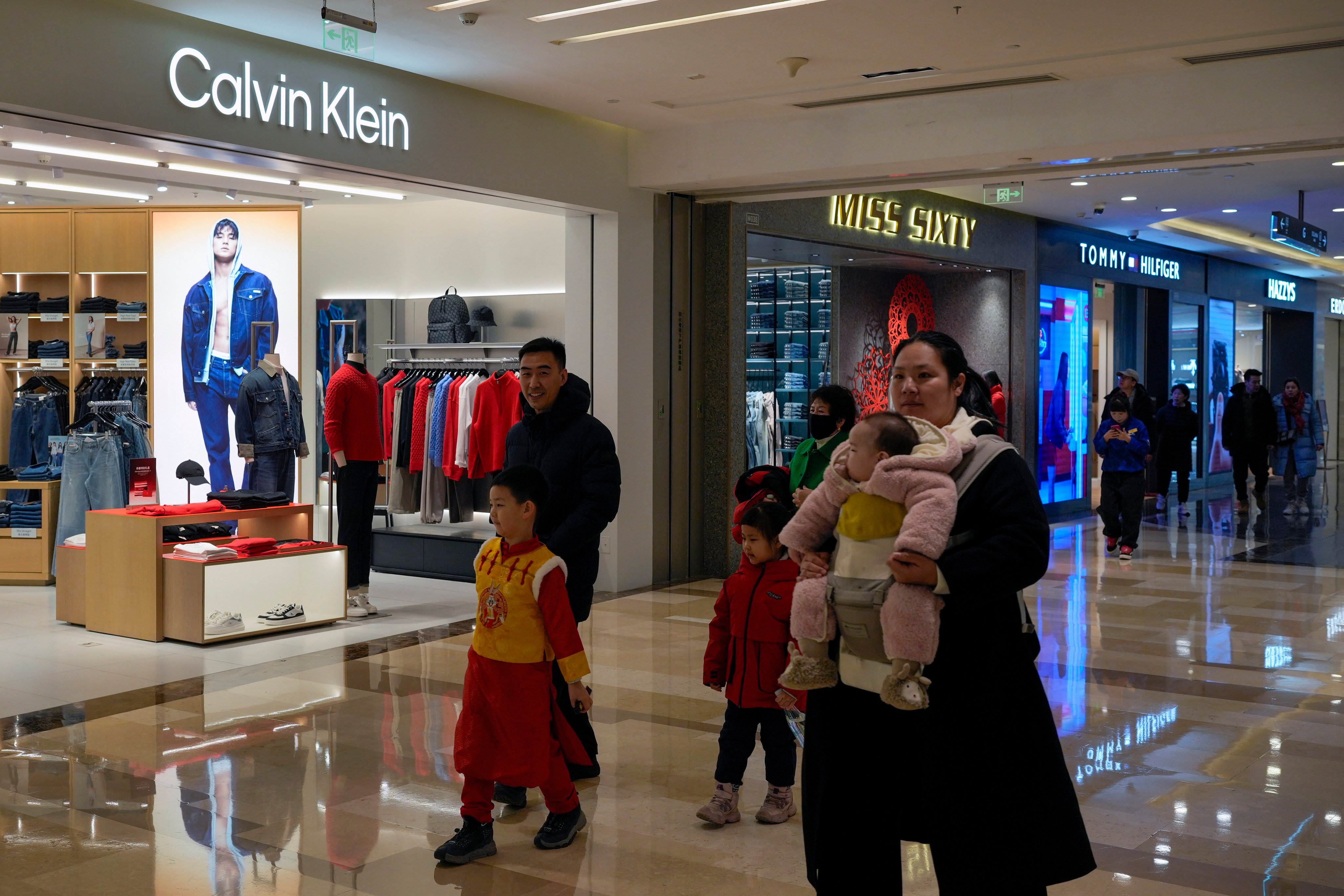 Shoppers walk past Calvin Klein and Tommy Hilfiger stores at a shopping centre in Beijing on Tuesday. Photo: AP