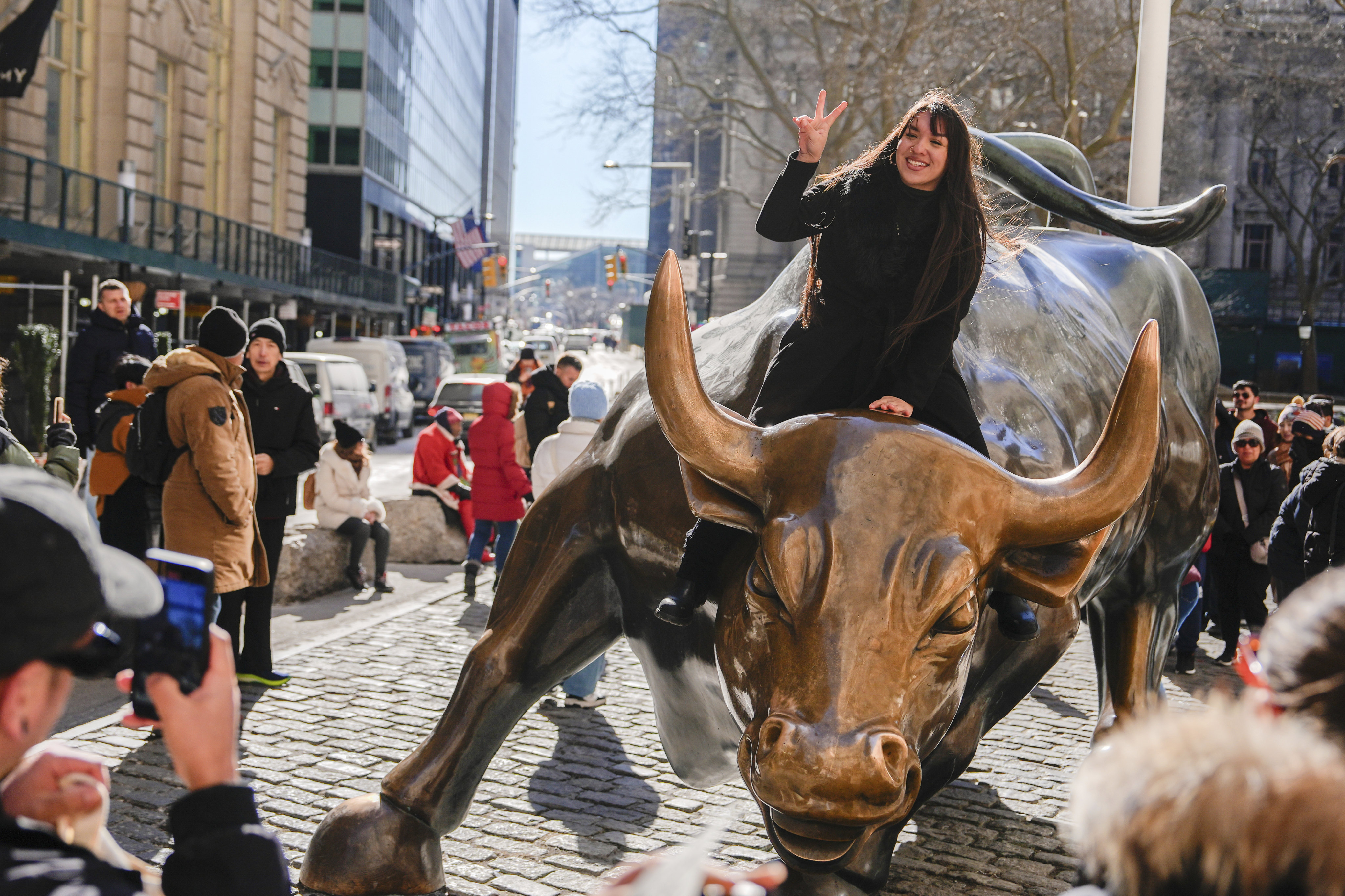 A woman poses for picture on the Wall Street bull statue near the New York Stock Exchange in New York. Photo: AP Photo