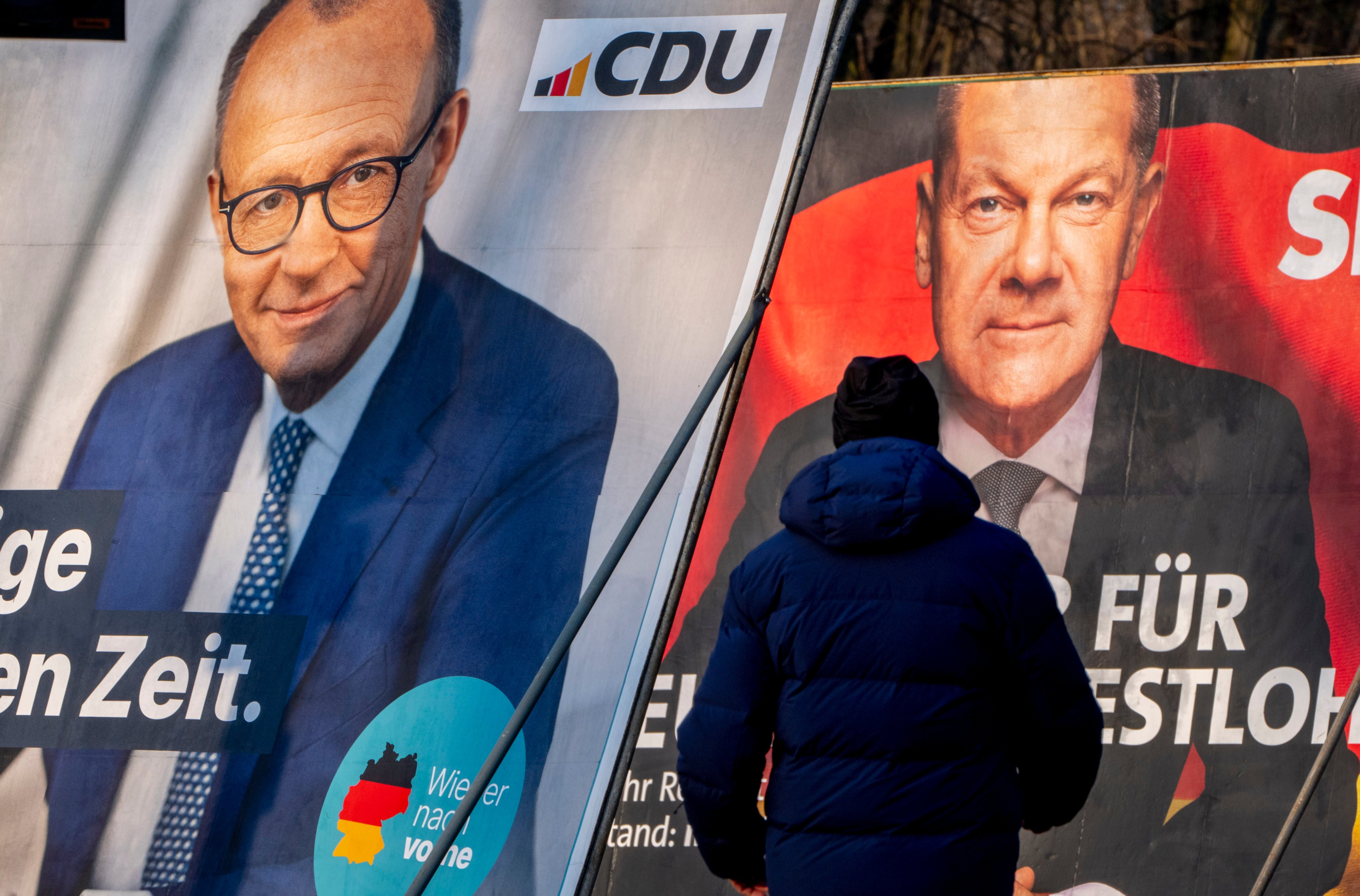 A man walks past election posters showing German Chancellor Olaf Scholz, right, and the conservative CDU’s candidate for chancellor Friedrich Merz, in Frankfurt, Germany, on Saturday. Photo: AP