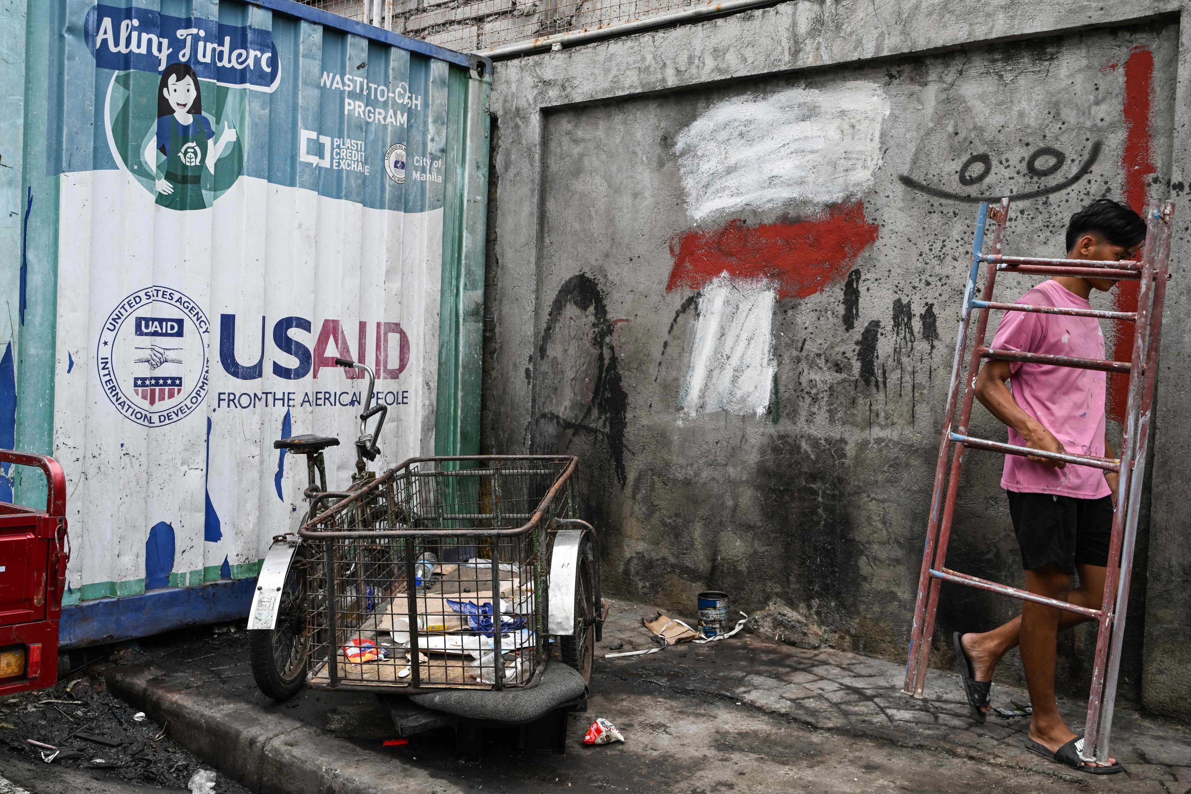 Signage for the US government’s humanitarian agency USAID is seen on a cargo container beside a tricycle in Manila on February 4. The US has issued a “stop-work” order for all existing foreign aid and paused new aid, after President Donald Trump ordered a pause to review if aid allocation was aligned with his foreign policy. Photo: AFP