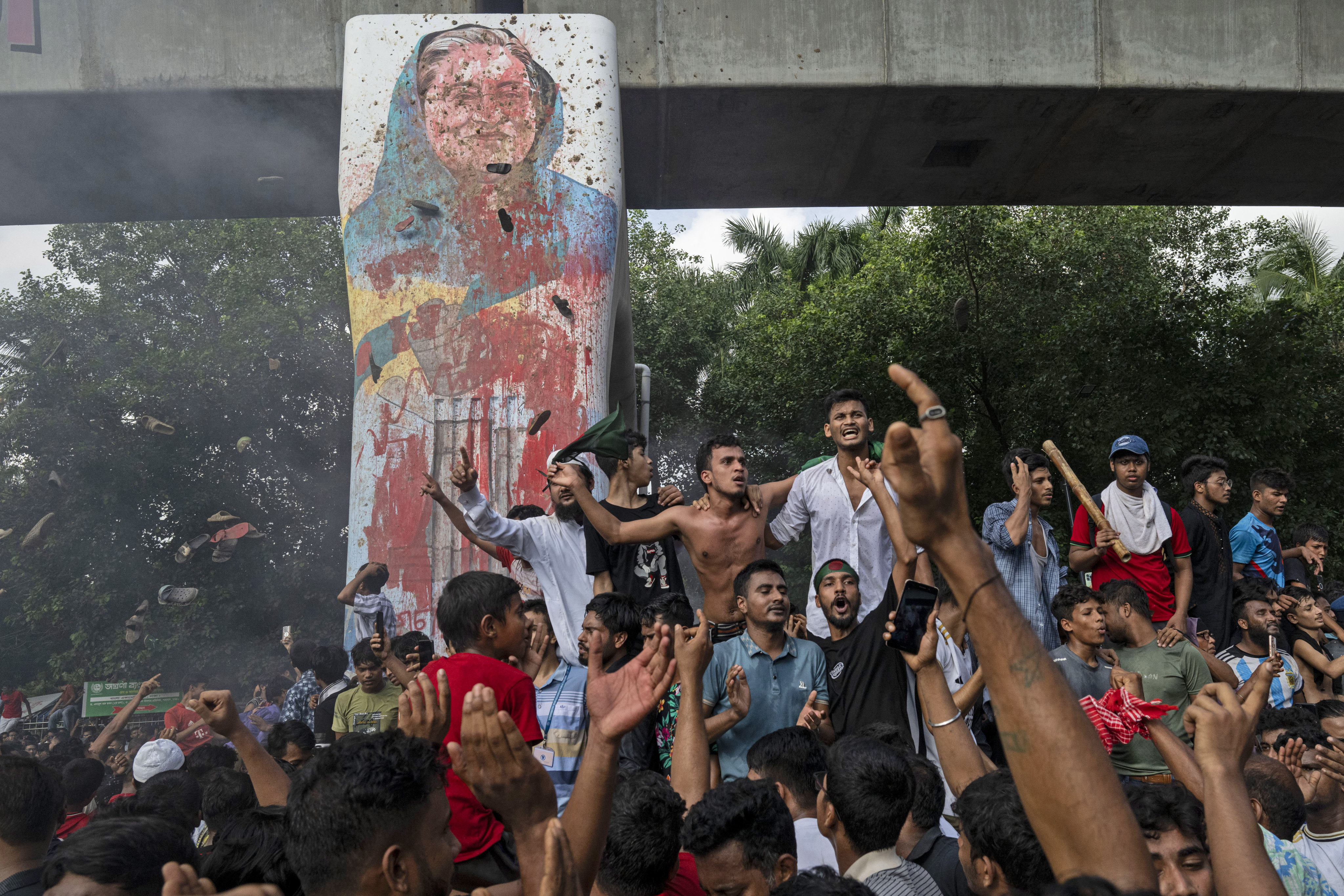 Protesters celebrate beside a defaced portrait of Prime Minister Sheikh Hasina after news of her resignation, in Dhaka, Bangladesh, on August 5, 2024. Photo: AP