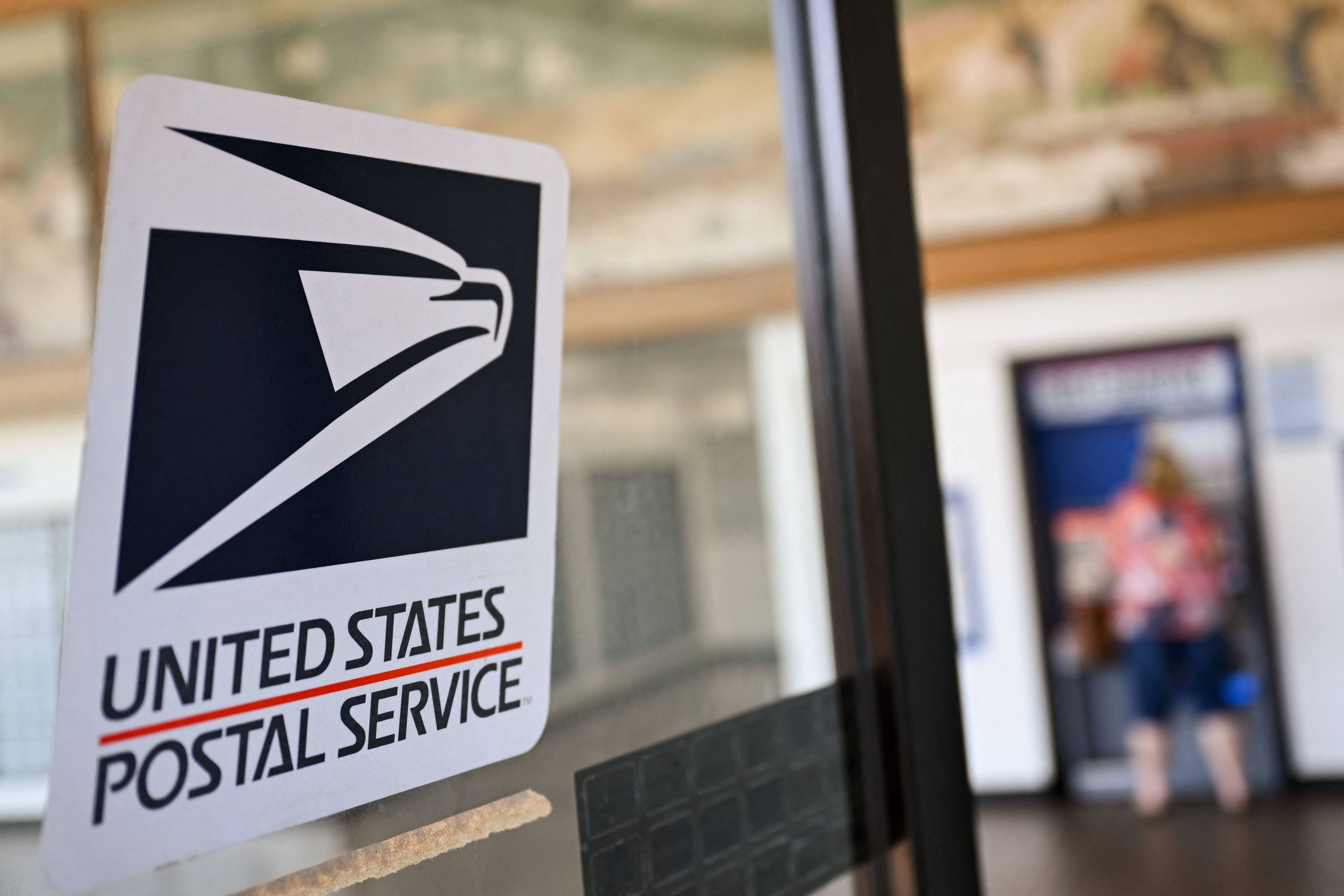 The United States Postal Service logo is displayed on a door as a postal customer uses a self-service mail shipping kiosk to ship a package at a post office in Redondo Beach, California, on August 28, 2024. It is estimated that the US received as many as 1.6 billion small parcels last year worth US$78 billion, amid an e-commerce boom. Photo: AFP