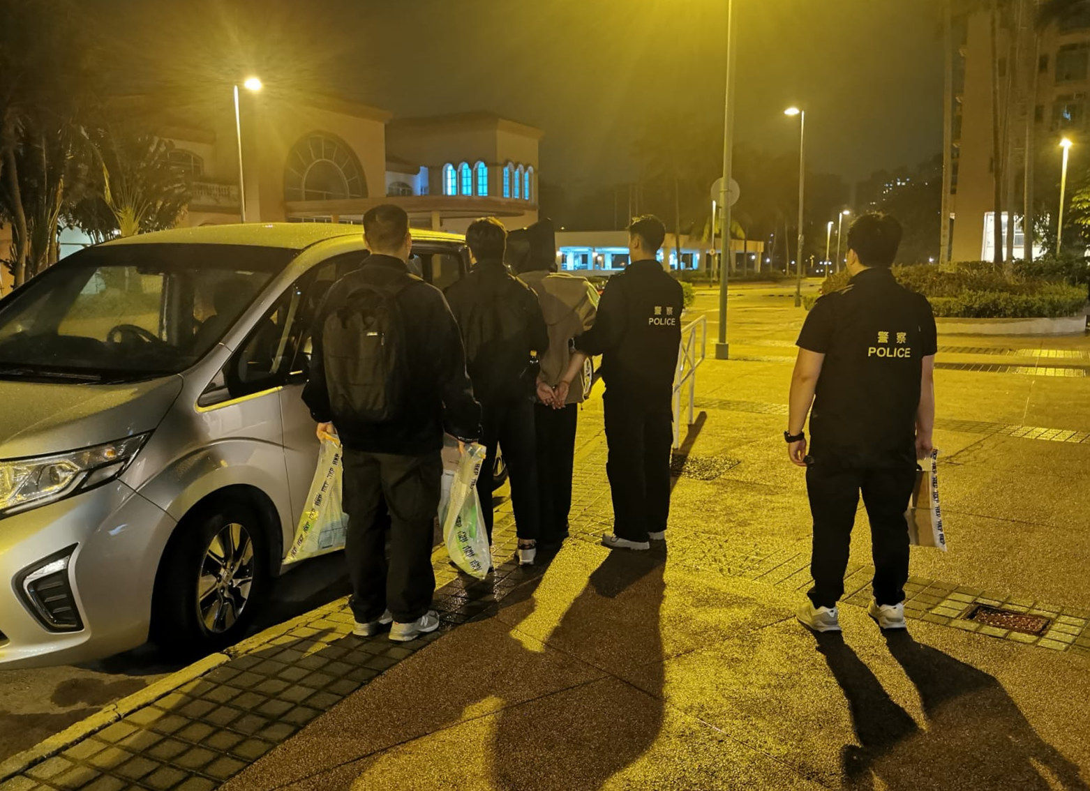 Police escort a suspect after intercepting him at a flat in Tuen Mun used as a drug storage and distribution centre. Photo: Handout