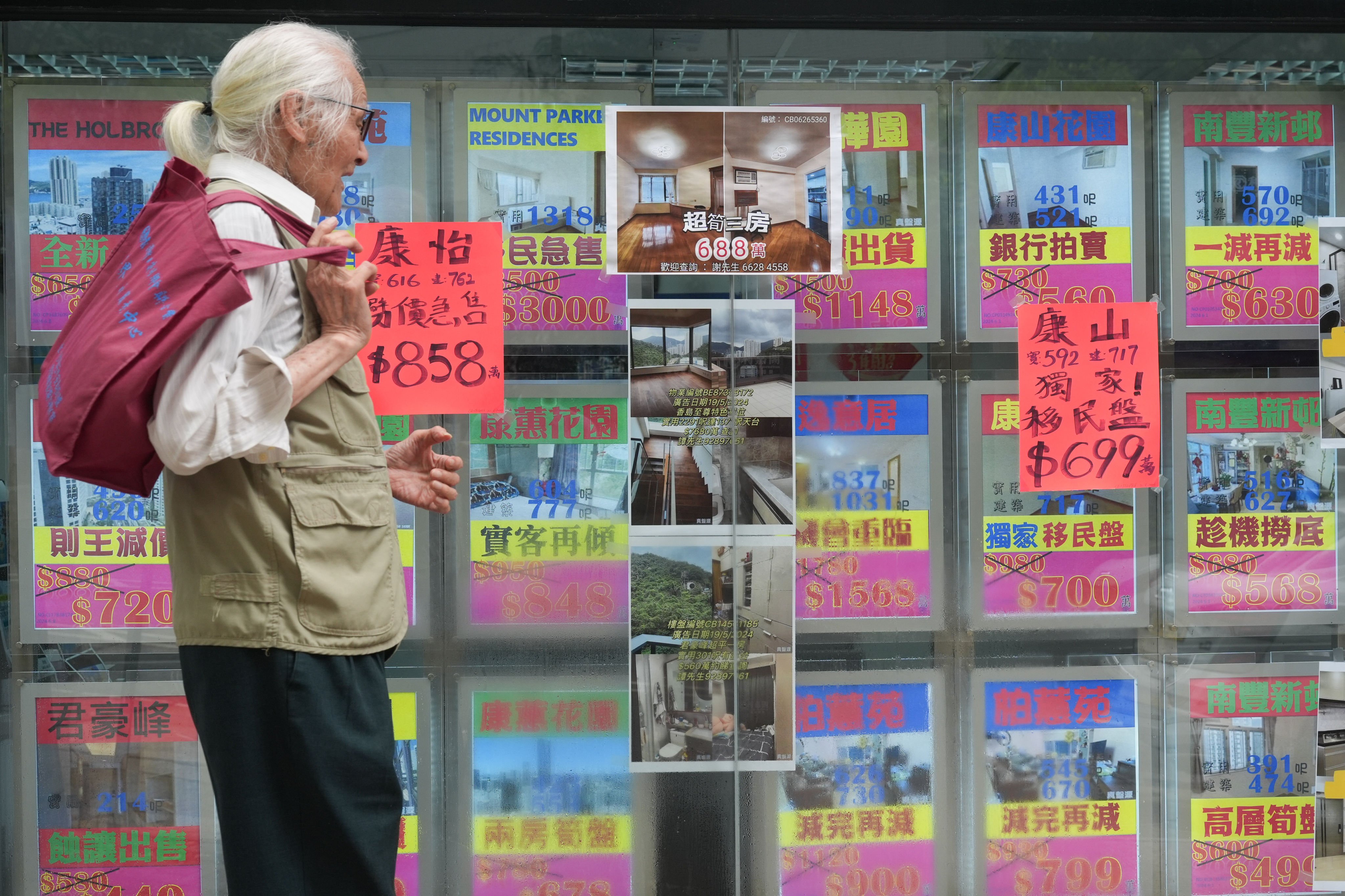 A pedestrian reacts to seeing home prices displayed by a property agency in Tai Koo, Hong Kong, on July 24. Photo: Eugene Lee