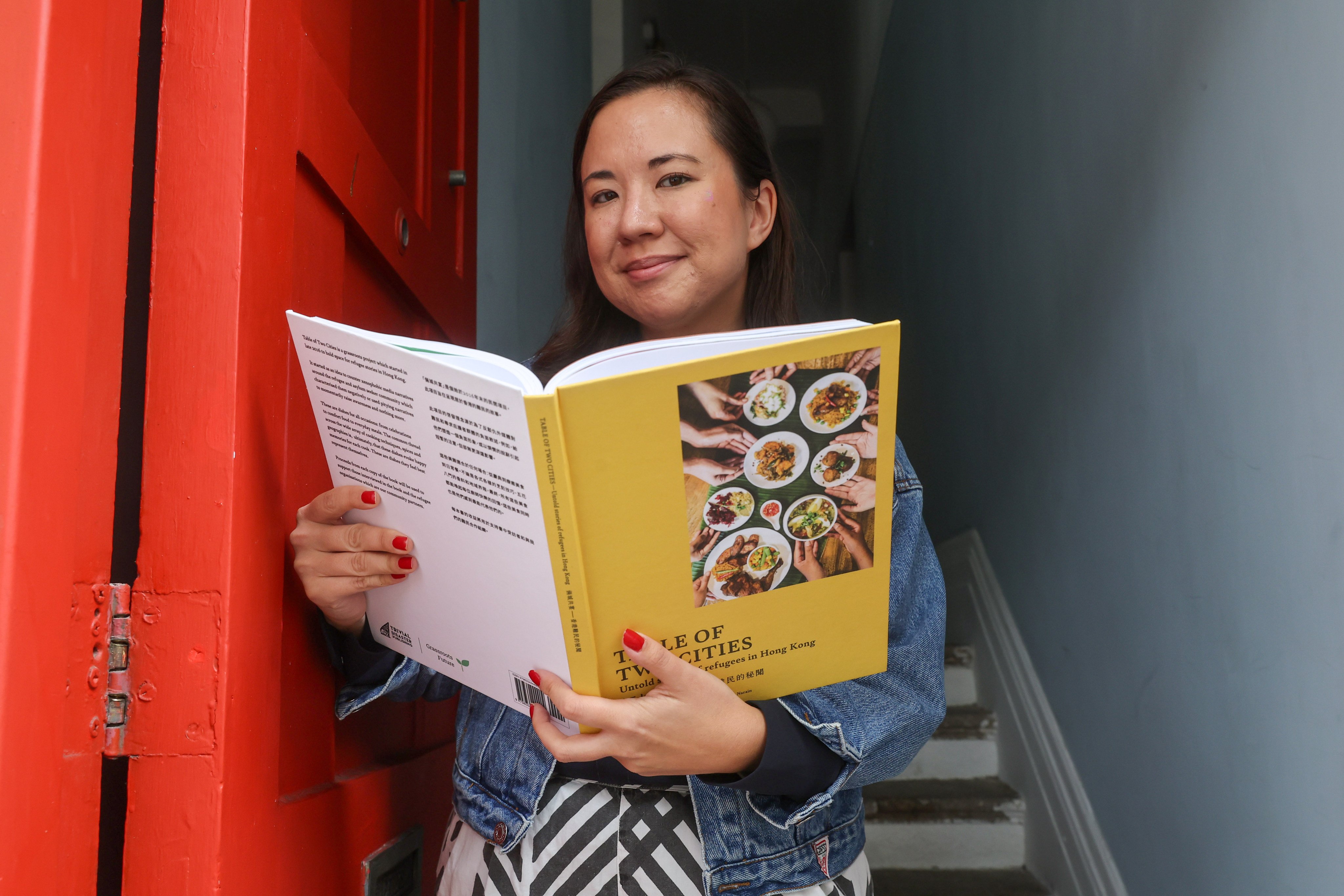 Tegan Smyth​​, founder of charity Grassroots Future, with a copy of Table of Two Cities, which features recipes shared by refugees and asylum seekers in Hong Kong, and their stories. Photo: Edmond So