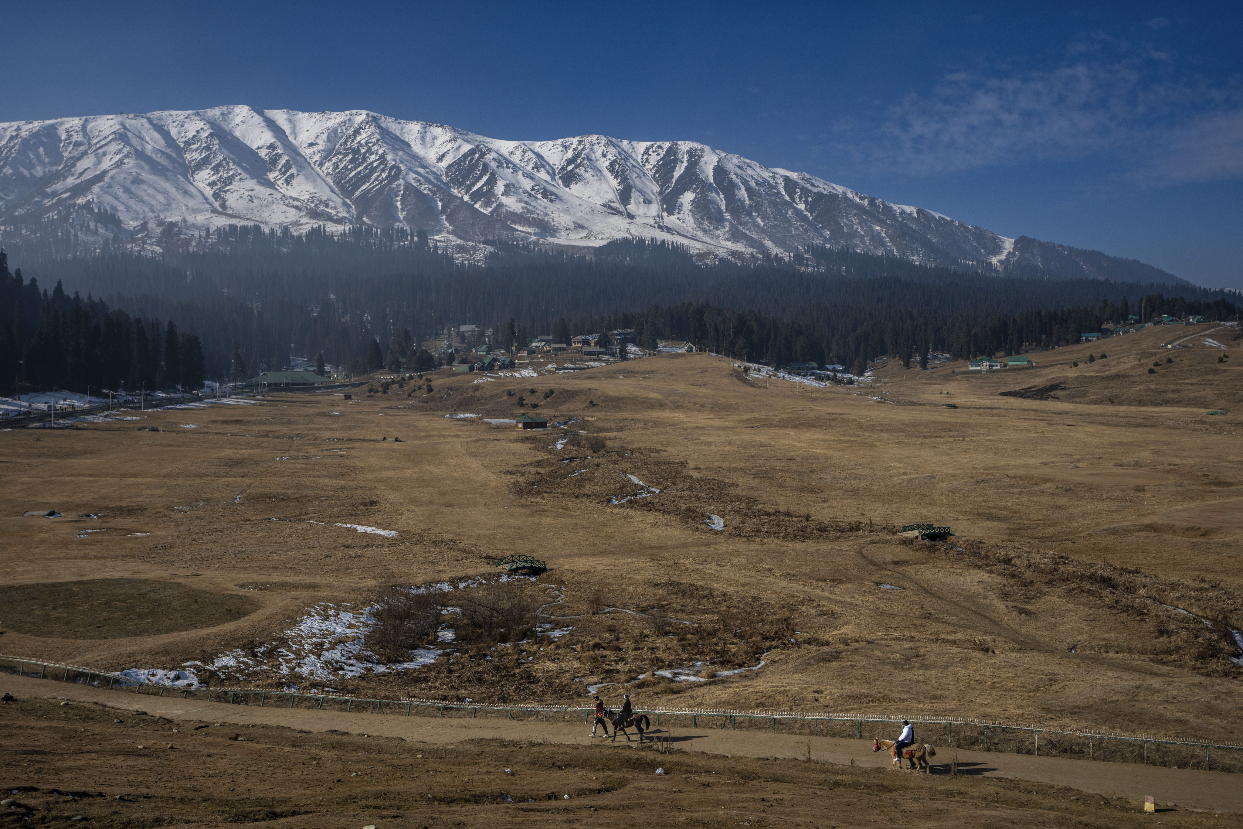 Tourists ride horses on grassy, snowless ski slopes in Gulmarg, Indian-administered Kashmir, in January last year. Photo: AP