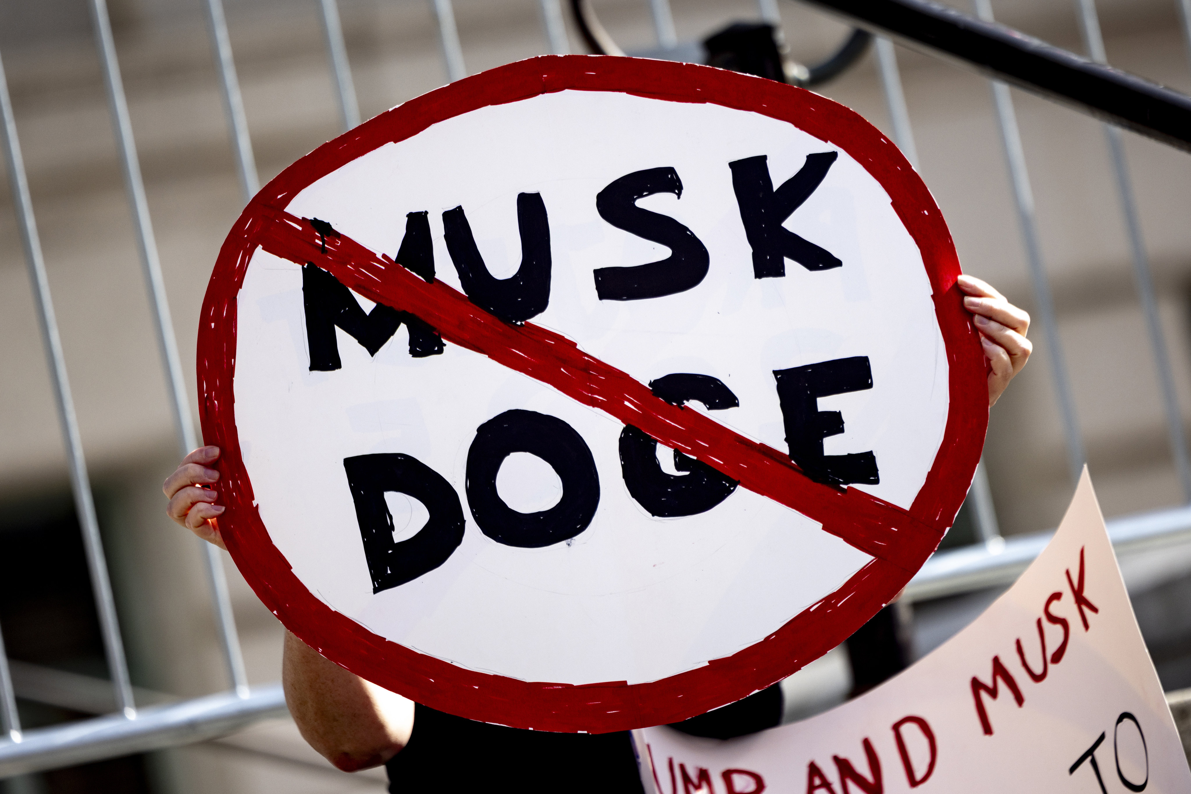 A demonstrator holds a poster displaying a prohibited traffic sign reading “Musk DOGE” during a rally to protest President Trump’s policies on February 17, 2025, in Los Angeles. Photo: AP