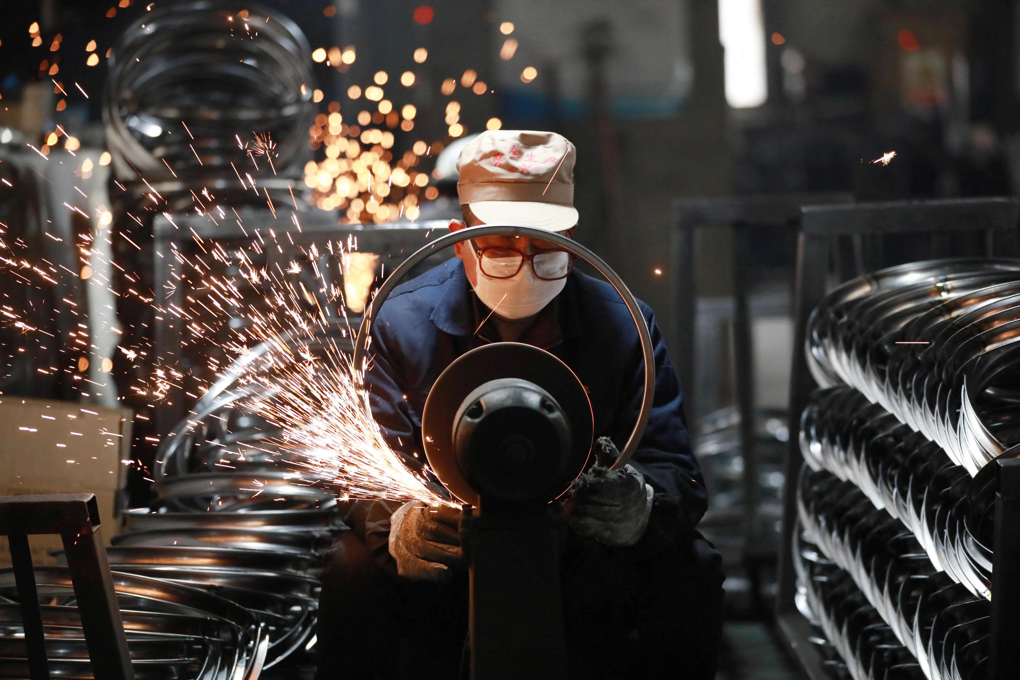 A worker polishes steel bicycle rims at a factory which produces bicycle parts for export, in Hangzhou, in eastern Zhejiang province, on February 11. Photo: AFP