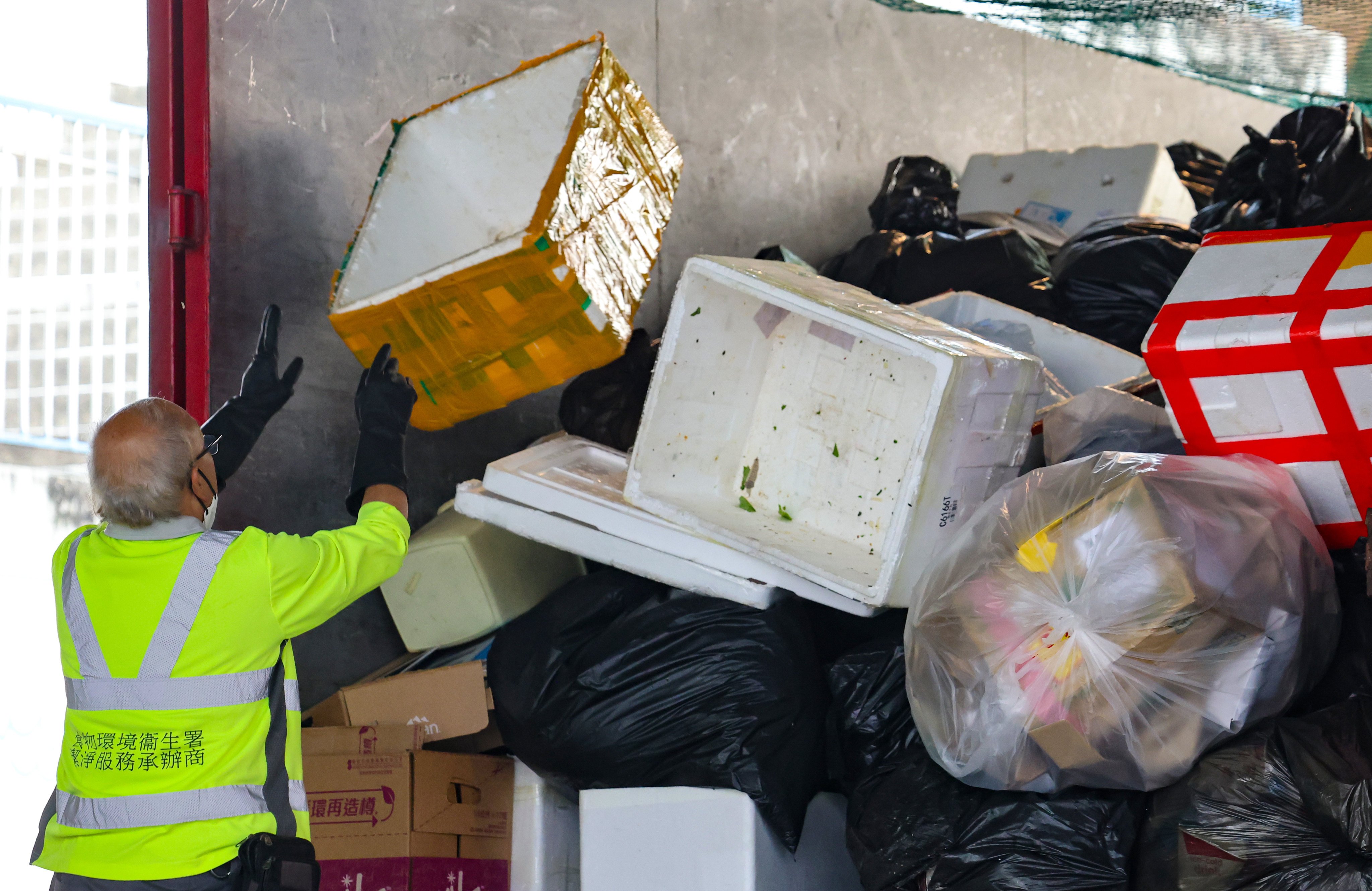 A cleaner outsourced by the Food and Environmental Hygiene Department to work on a refuse collection vehicle at Haiphong Road in Tsim Sha Tsui. Photo: Jelly Tse