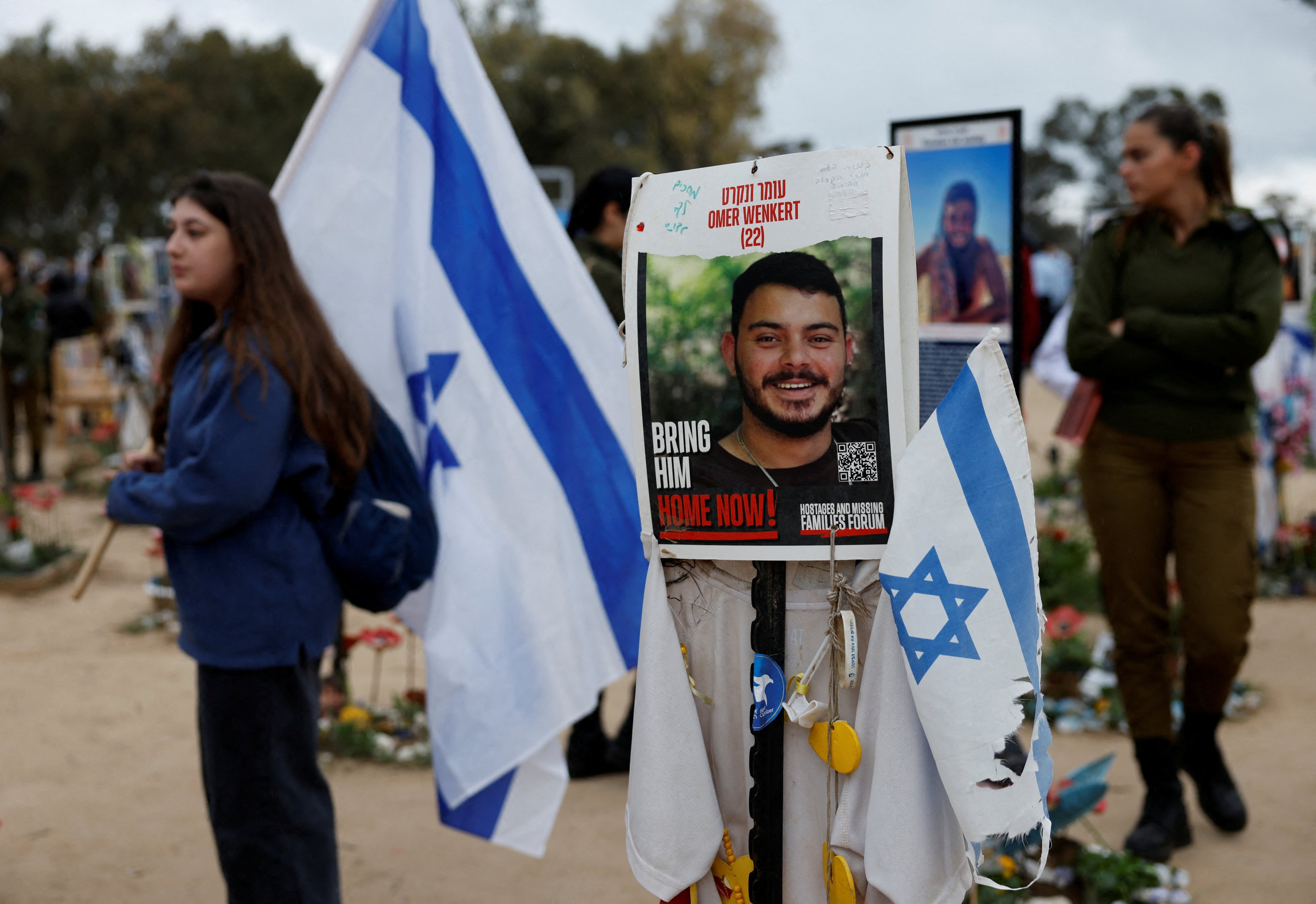 People walk near a poster of hostage Omer Wenkert, at the site of the Nova festival where party goers were killed and kidnapped during the October 7 Hamas attack. Hamas signalled on Wednesday that it was willing to free all remaining hostages held in Gaza in a single swap during the next phase of the ongoing ceasefire agreement. Photo: Reuters