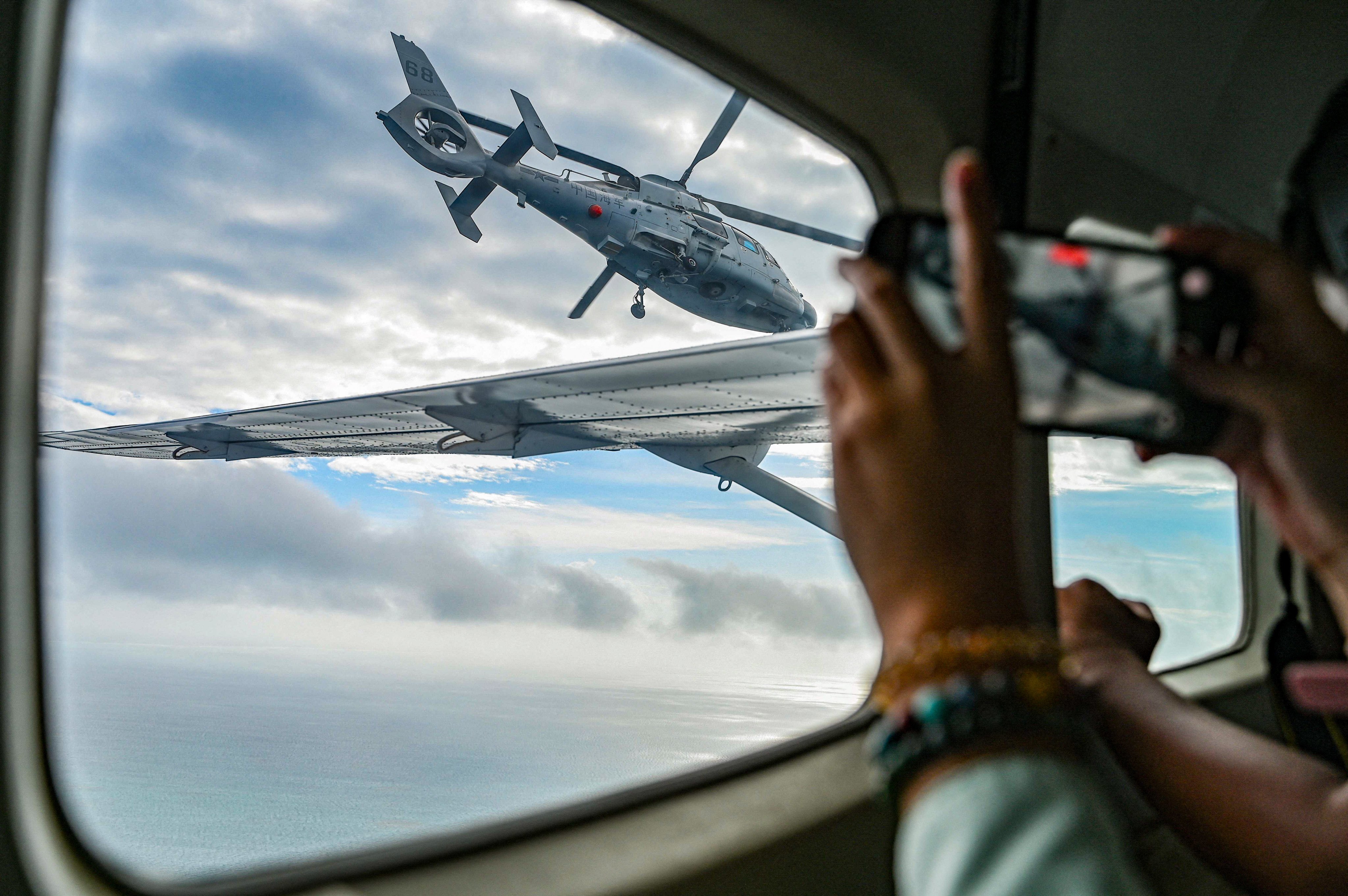 An aircraft identified by the Philippine Coast Guard as a Chinese navy helicopter flies near the Philippine fisheries bureau plane at Scarborough Shoal in the South China Sea on February 18. Photo: AFP