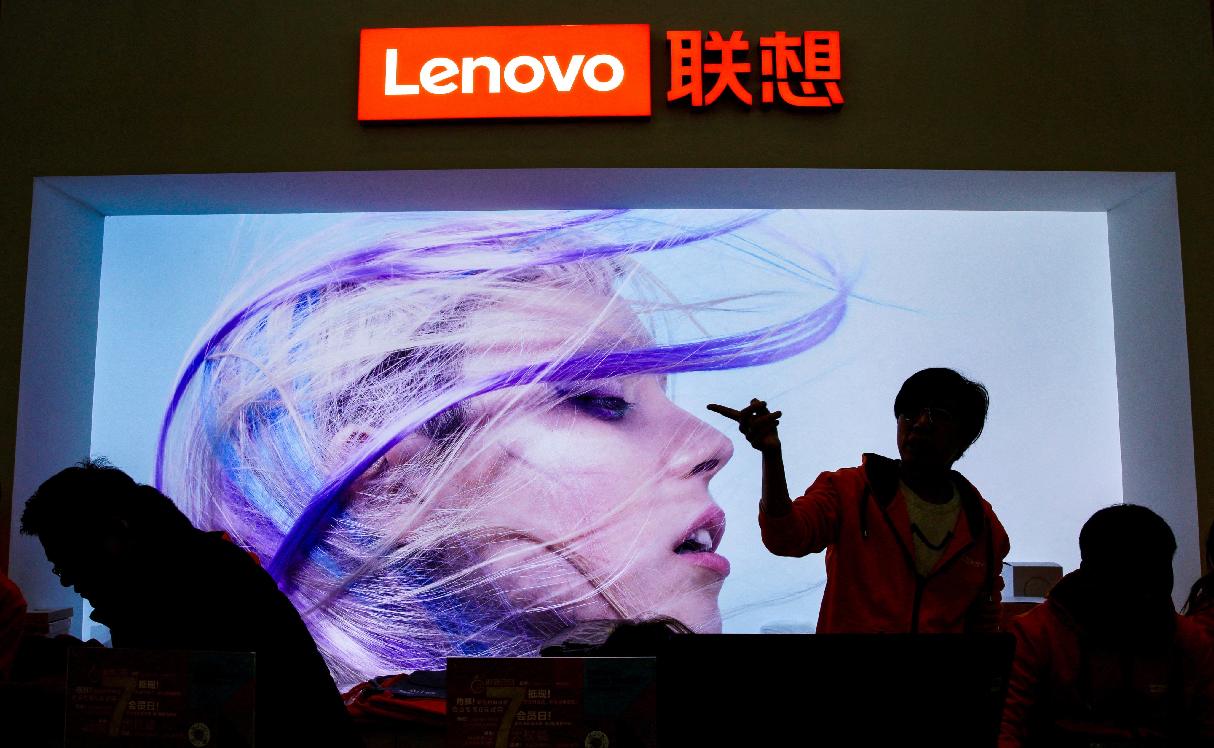 An employee gestures next to a Lenovo logo at Lenovo Tech World in Beijing on November 15, 2019. Photo: Reuters