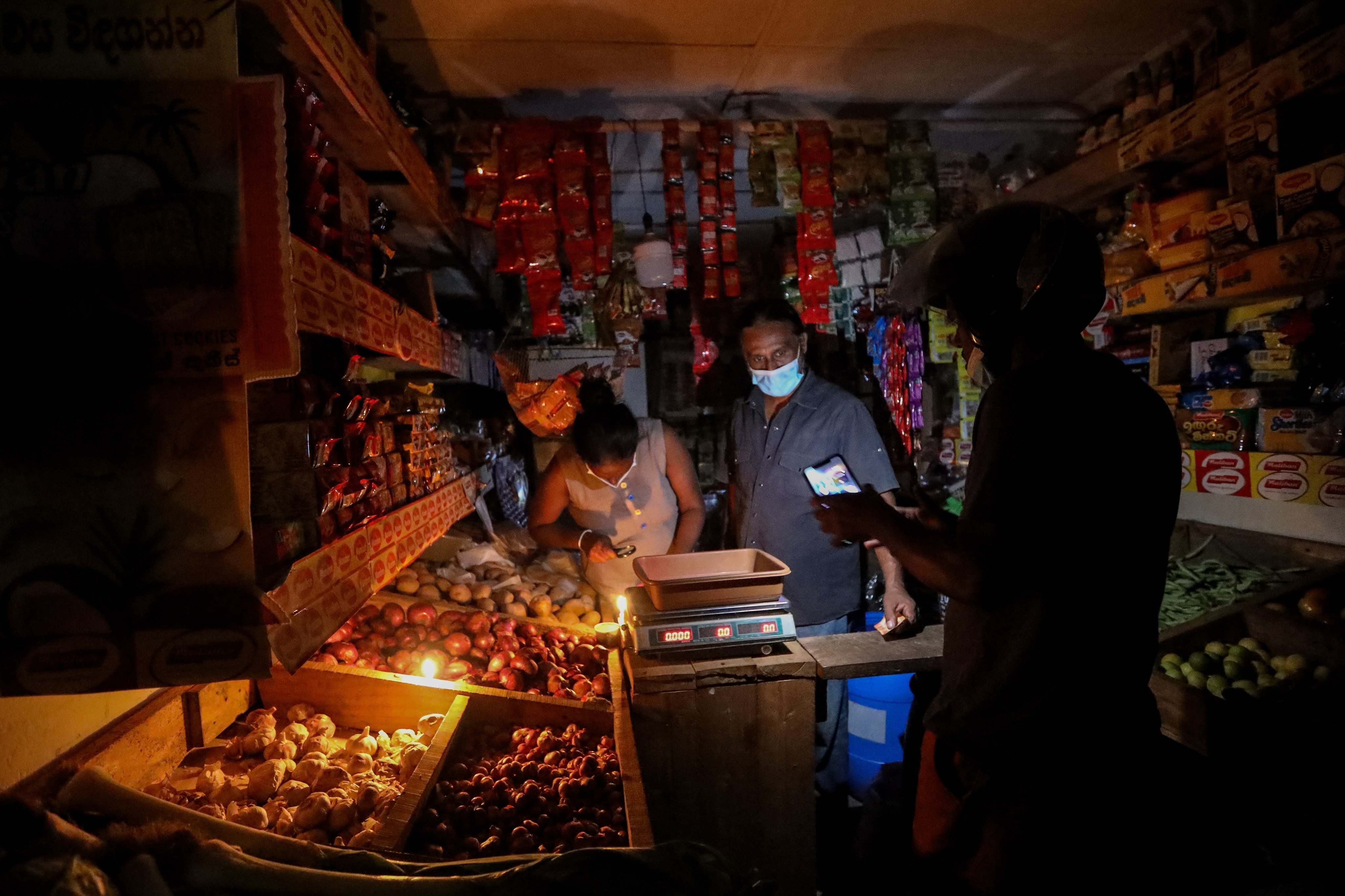 A grocery vendor illuminates his shop with candlelight amid power cuts in Colombo, Sri Lanka. Photo: EPA-EFE