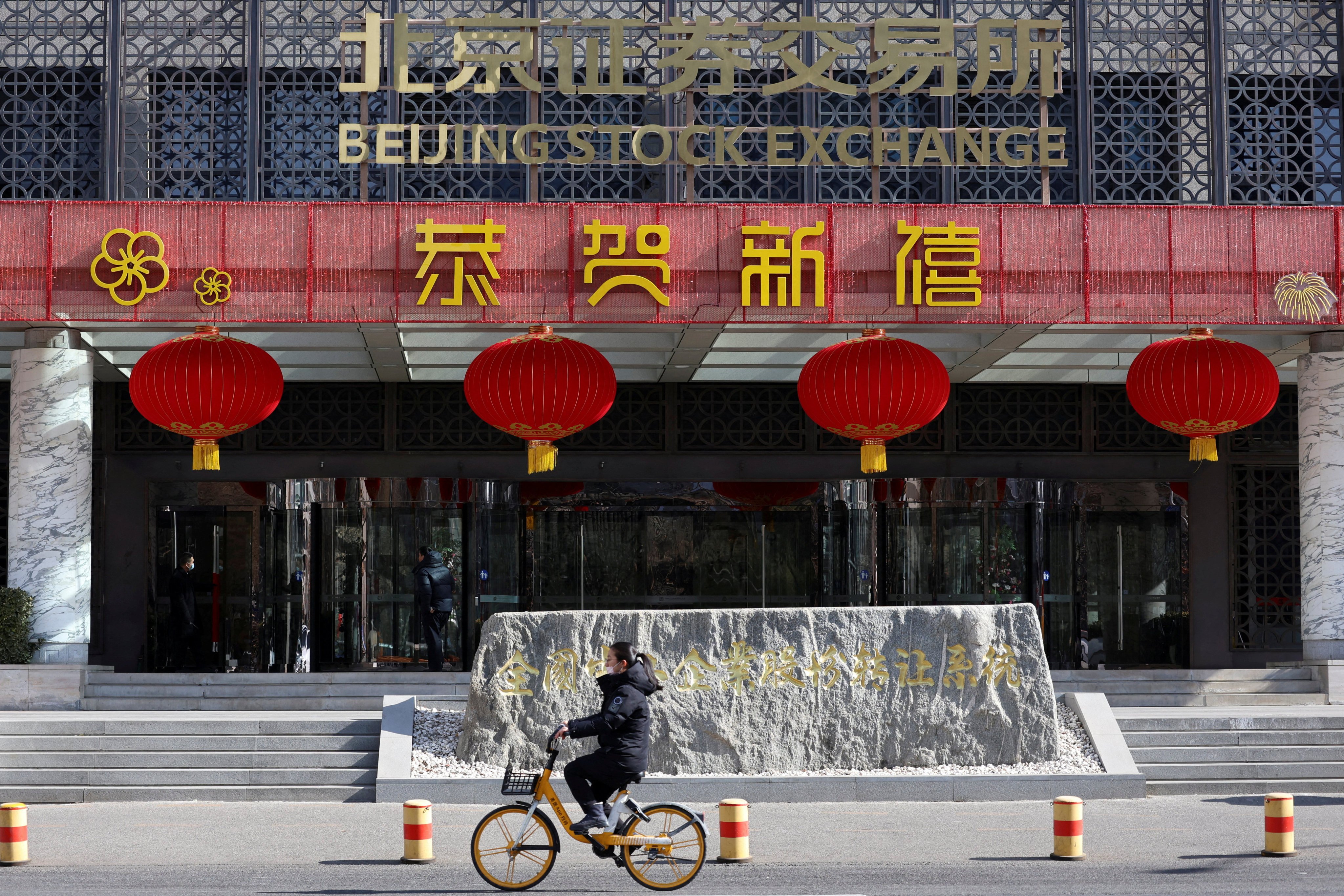 A woman cycles past the Beijing Stock Exchange. China could relax curbs to help companies launch IPOs. Photo: Reuters