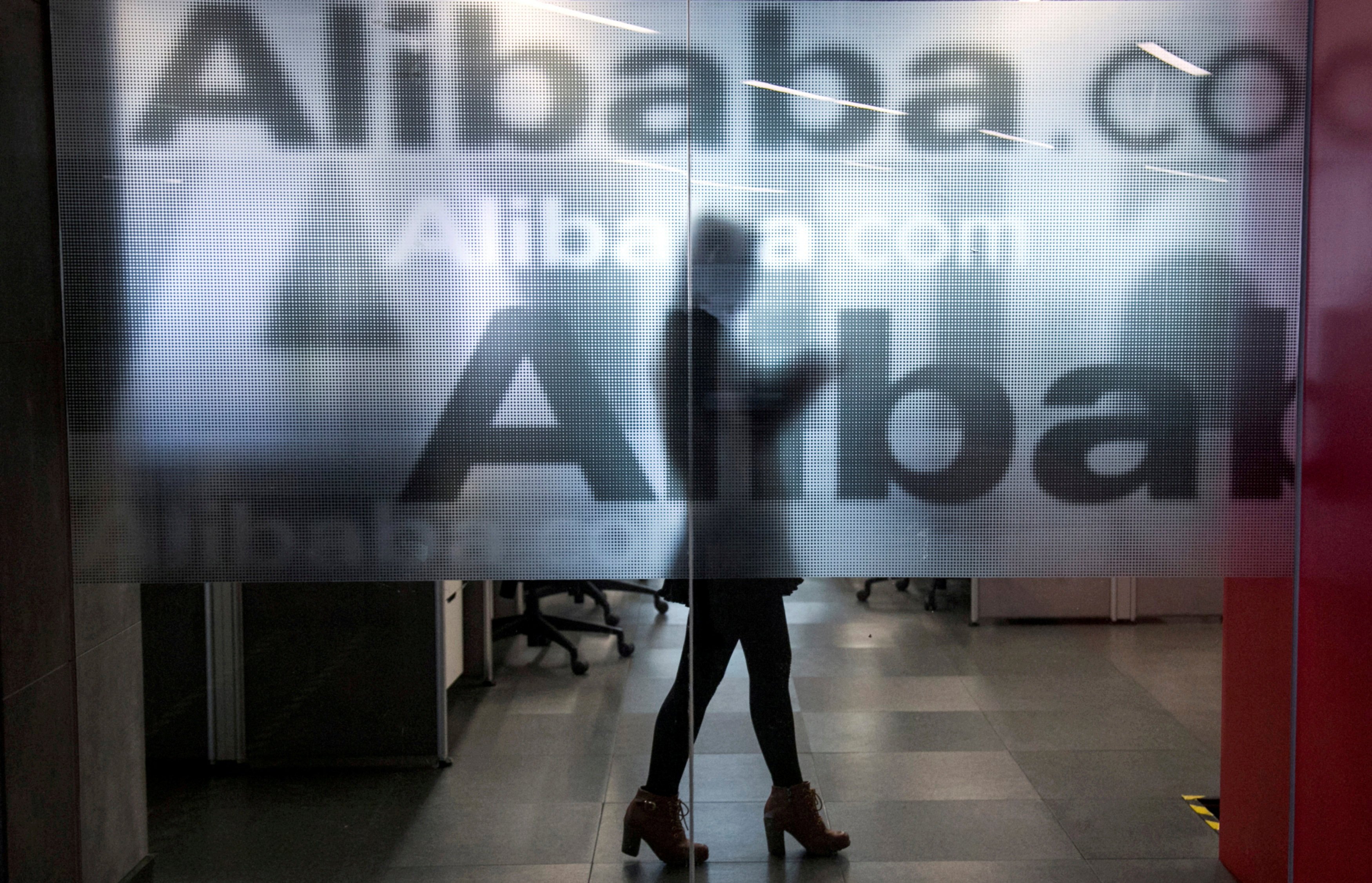 An employee walks behind a glass wall with the logo of Alibaba at the company’s headquarters in Hangzhou, Zhejiang province. File photo: Reuters