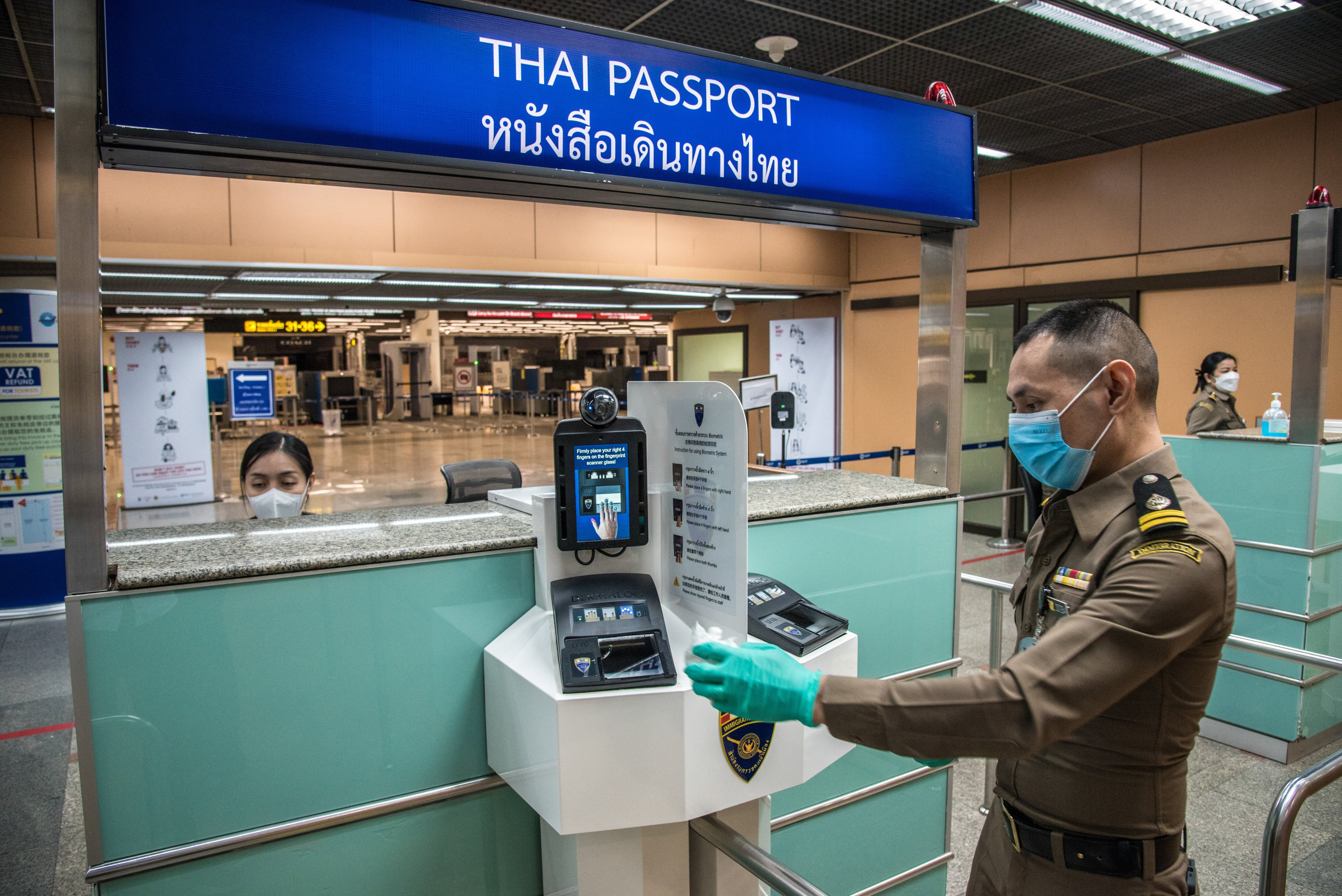 Immigration officers cleaning a fingerprint scanner at Don Muang International Airport in 2021. Photo: Getty Images