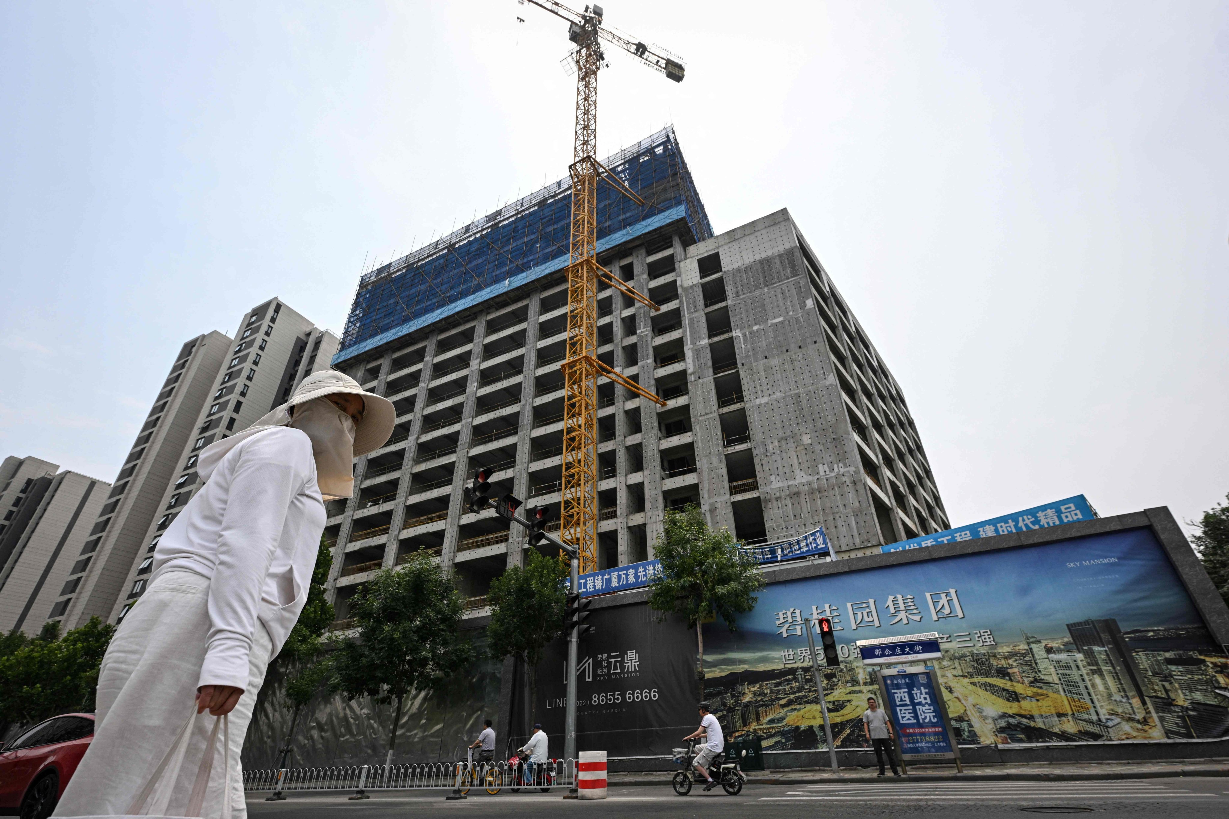 A woman walks past a housing complex under construction in Tianjin, on June 5, 2024. Photo: AFP