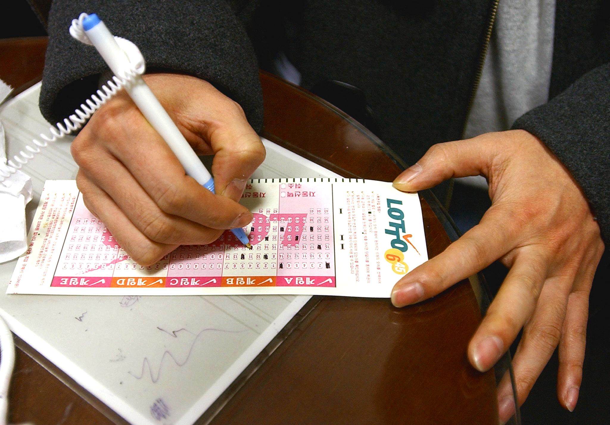 A man marks numbers on a lottery ticket in Seoul. Photo: AFP