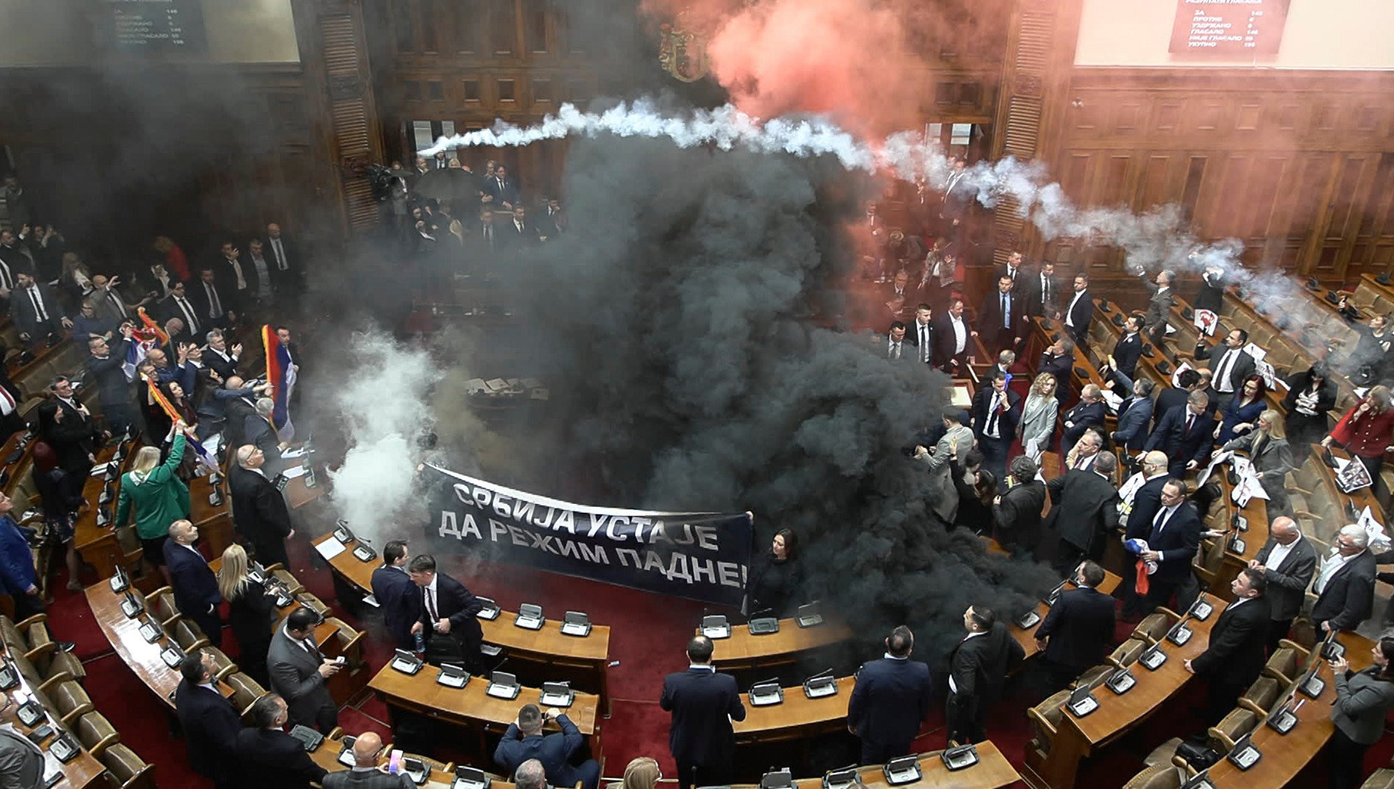 Smoke bombs and flares being tossed in Serbia’s parliament. Photo: RTS Serbia via AP