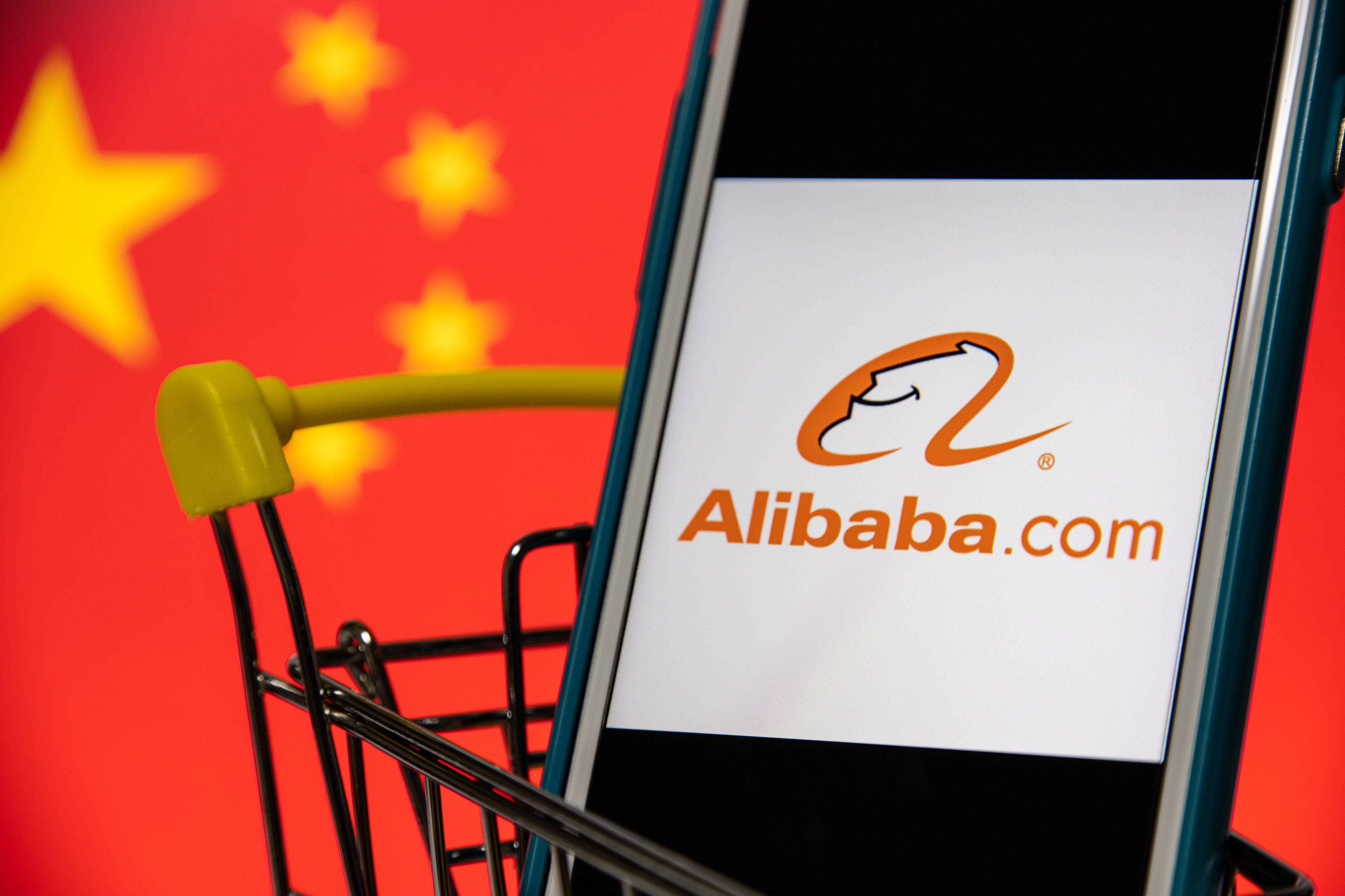 Kumamoto / JAPAN - Oct 3 2020 : Alibaba.com logo on iPhone in cart with Chinese flag. Alibaba Group, Chinese multinational conglomerate holding, is the world&#39;s largest retailer and e-commerce company.