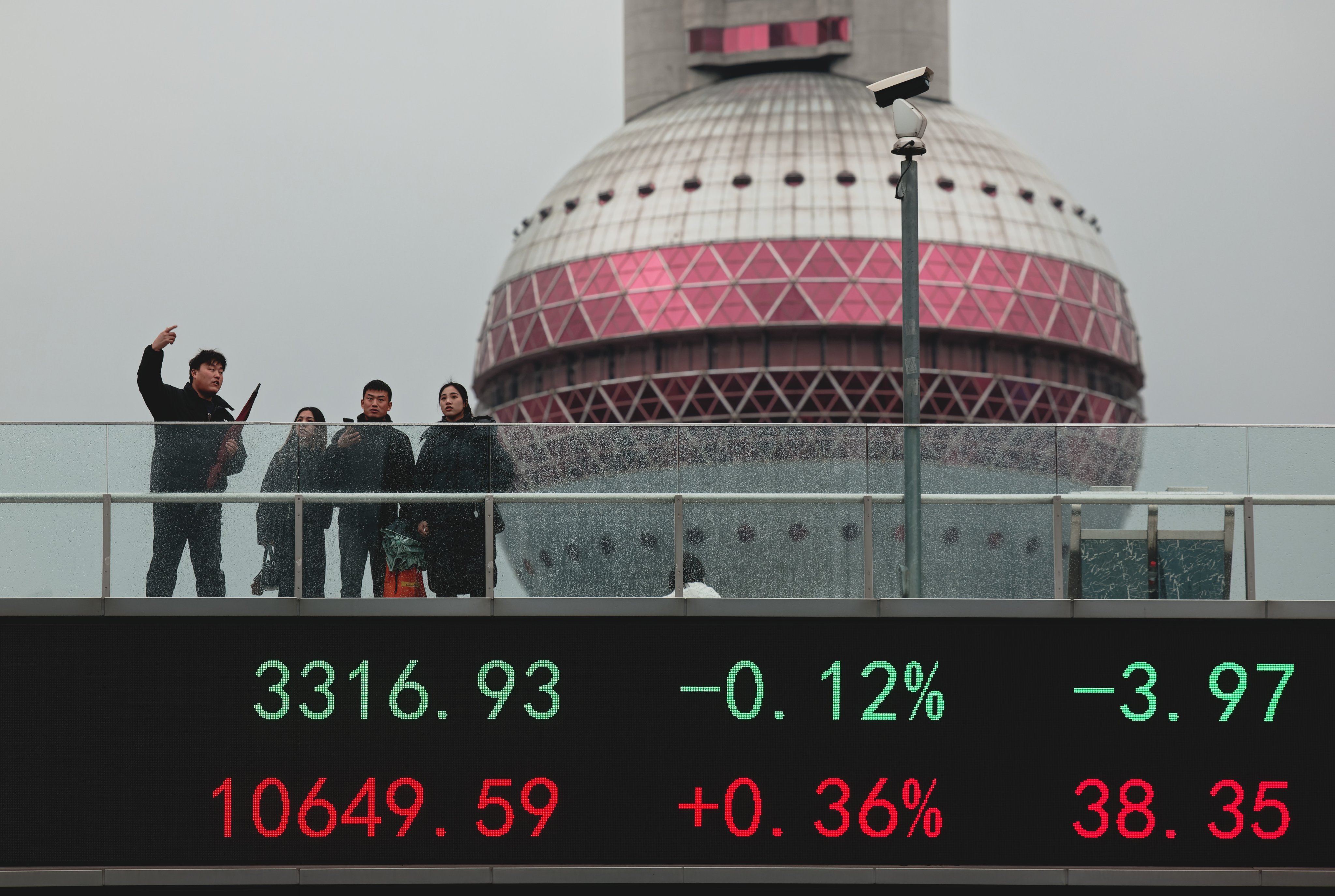 People stand on a pedestrian bridge with a display showing stock data in Shanghai on March 3, 2025. Photo: EPA-EFE