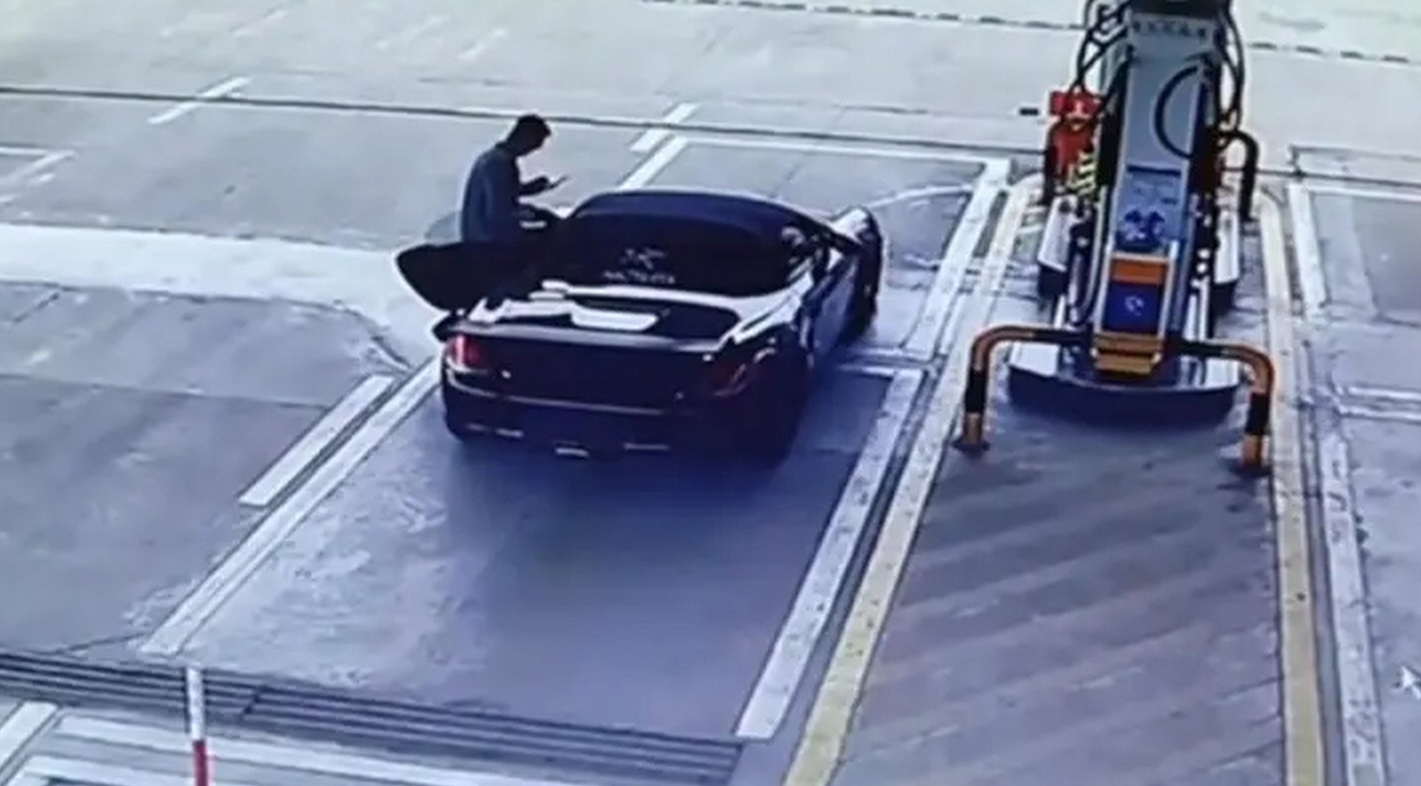The Porsche driver stands at the door of his vehicle after arriving at the petrol station. Photo: QQ.com