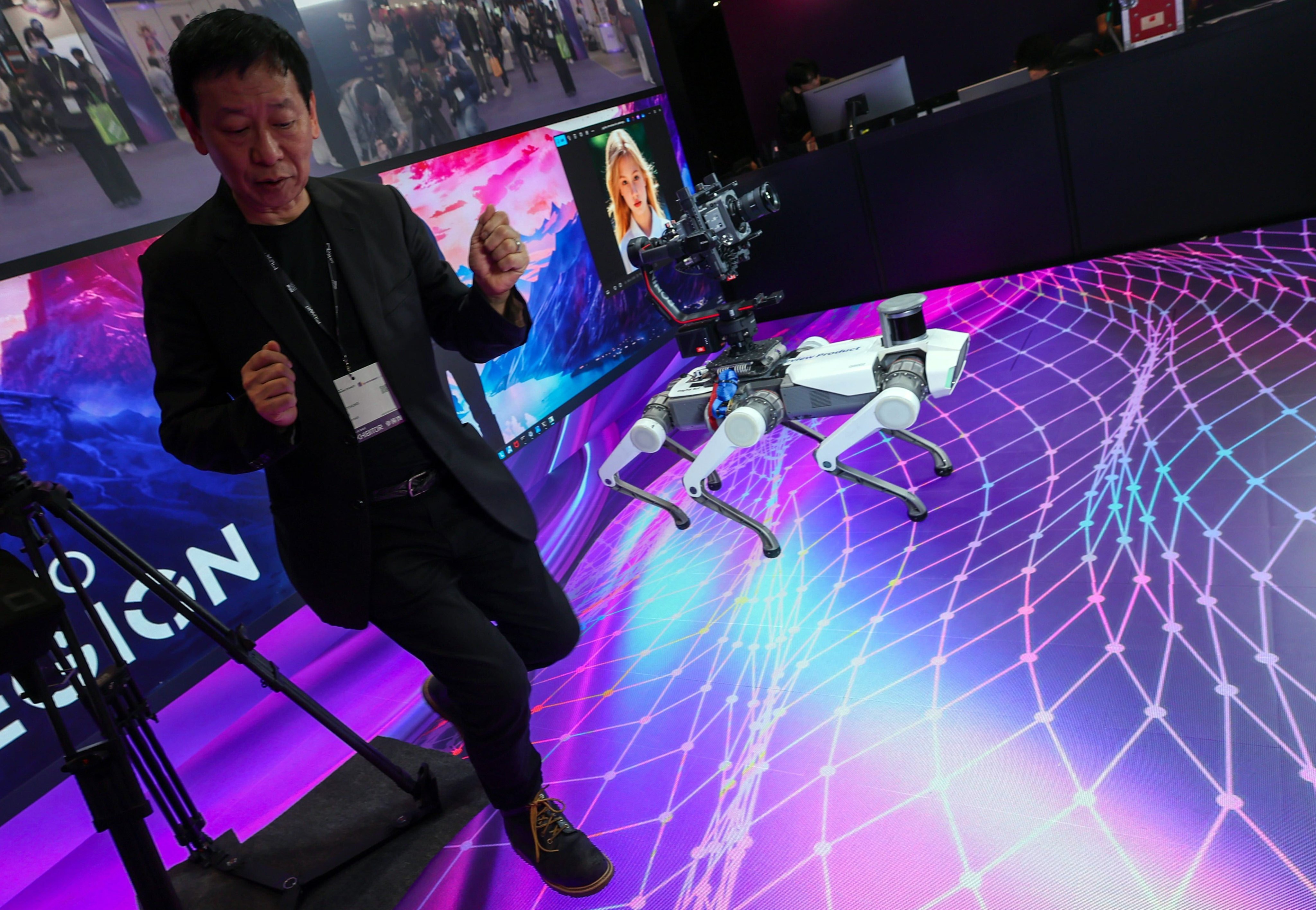 A visitor dances along with a robodog designed by Lenovo that was on display at the AI Hub during the Entertainment Expo 2025 at Hong Kong Convention and Exhibition Centre in Wan Chai on March 17. Photo: Dickson Lee