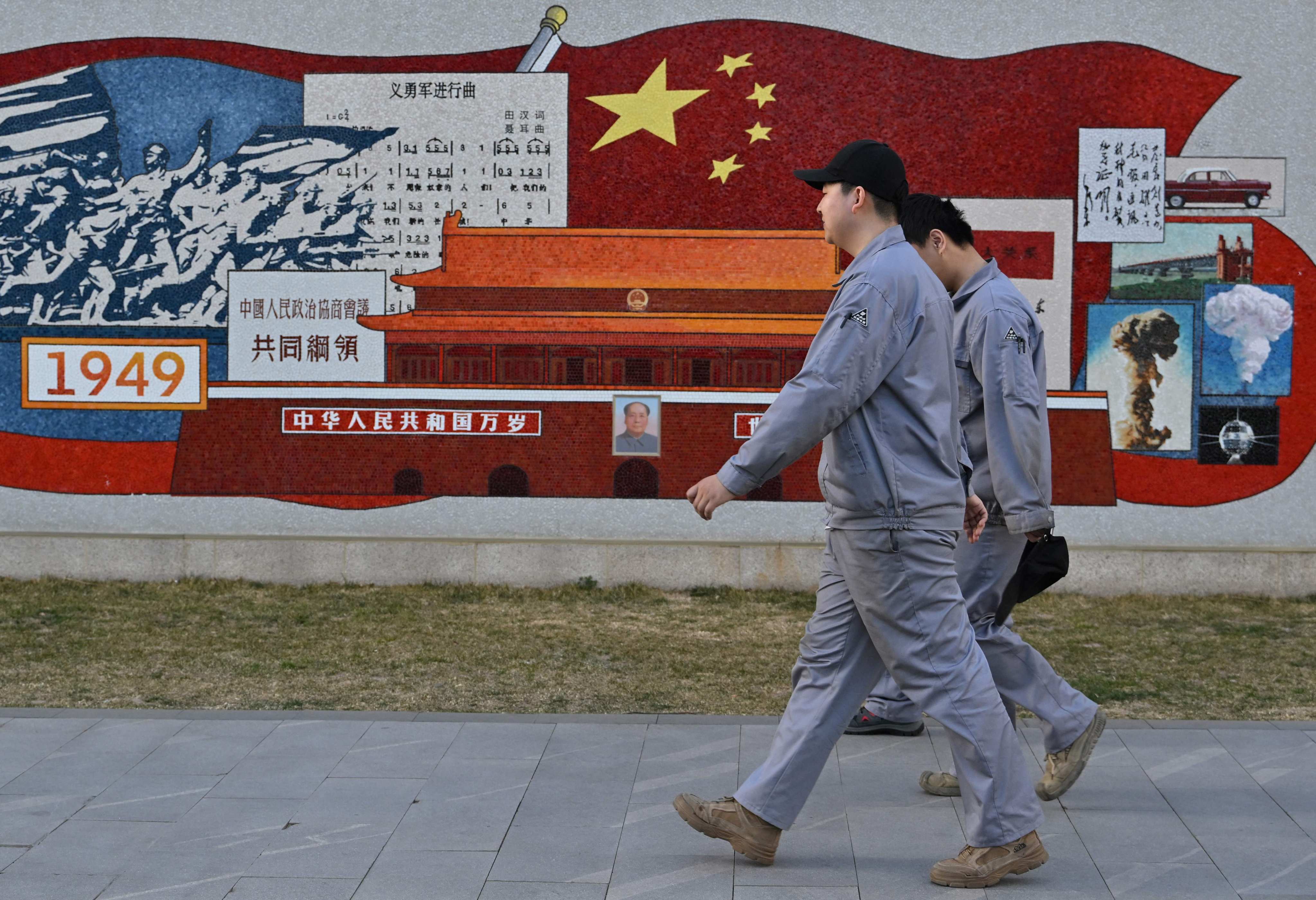 Workers walk past a mural depicting China’s history at the Zhongguancun No 1, an incubation platform for tech companies, in Beijing on March 19, 2025. Photo: AFP