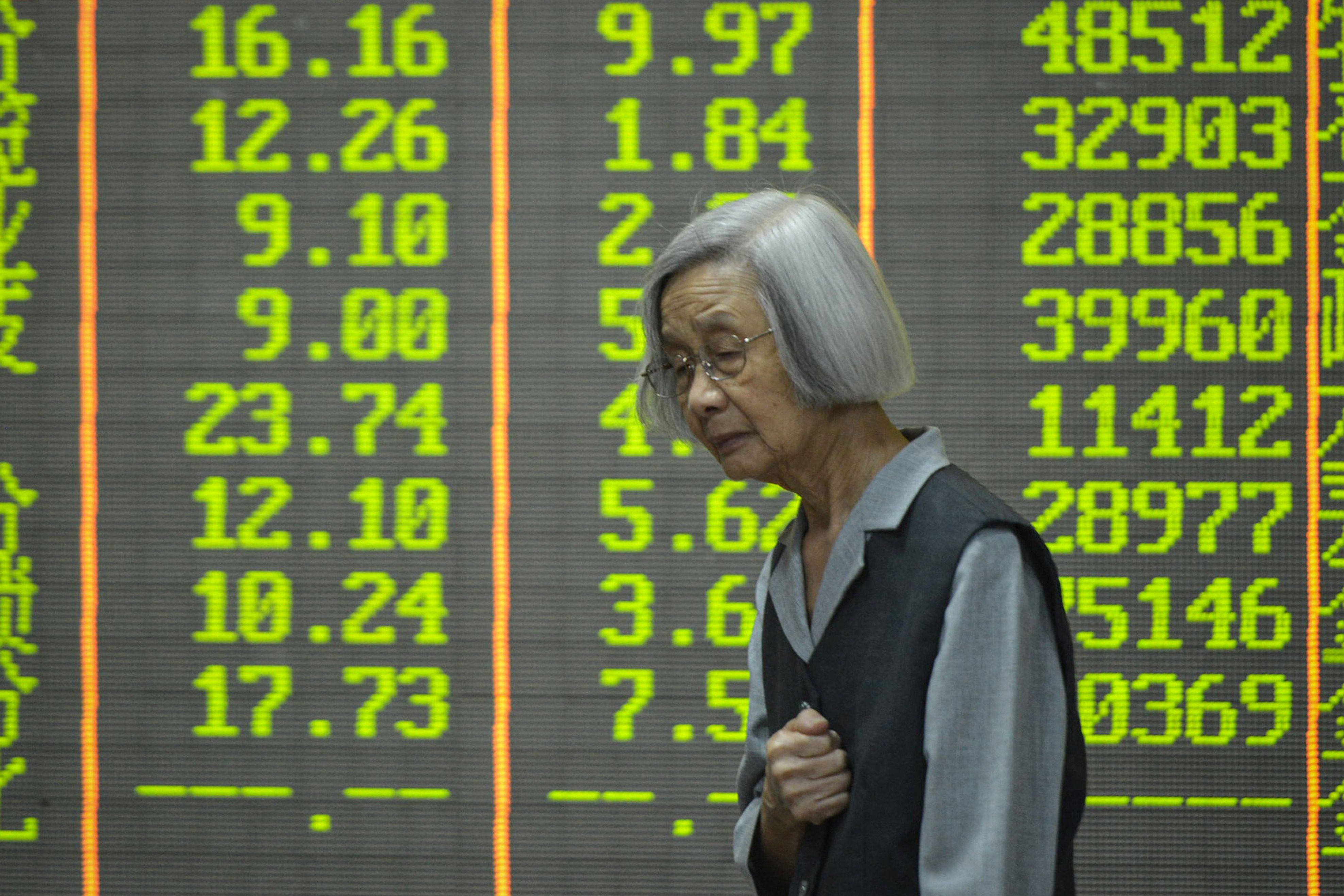 A woman walks past a screen showing stock market movements at a securities company in Hangzhou, in eastern China’s Zhejiang province. Photo: AFP