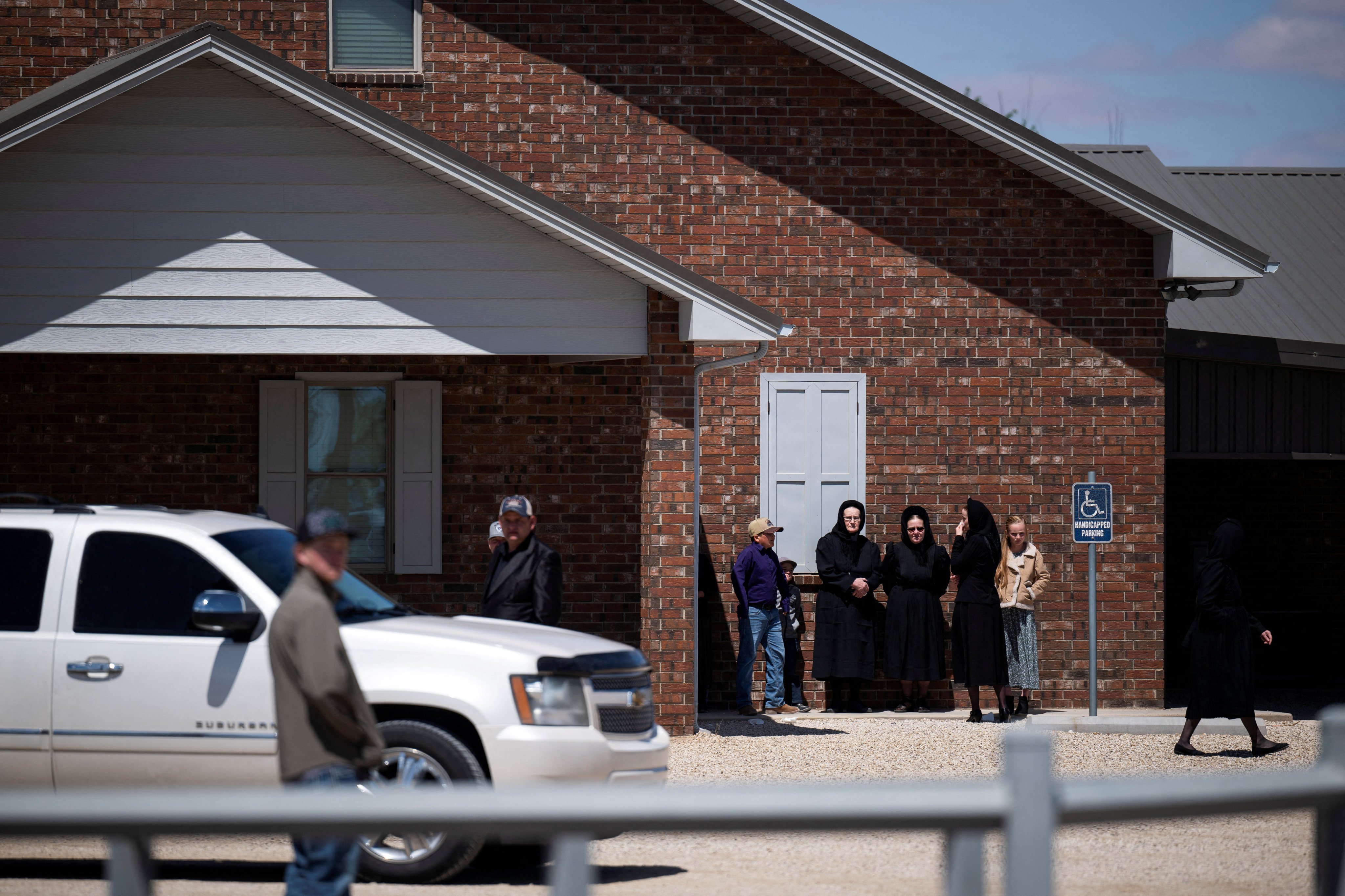 People stand outside a Mennonite church after a funeral for an eight-year-old girl who died of measles in Texas, US. Photo: The Texas Tribune via Reuters