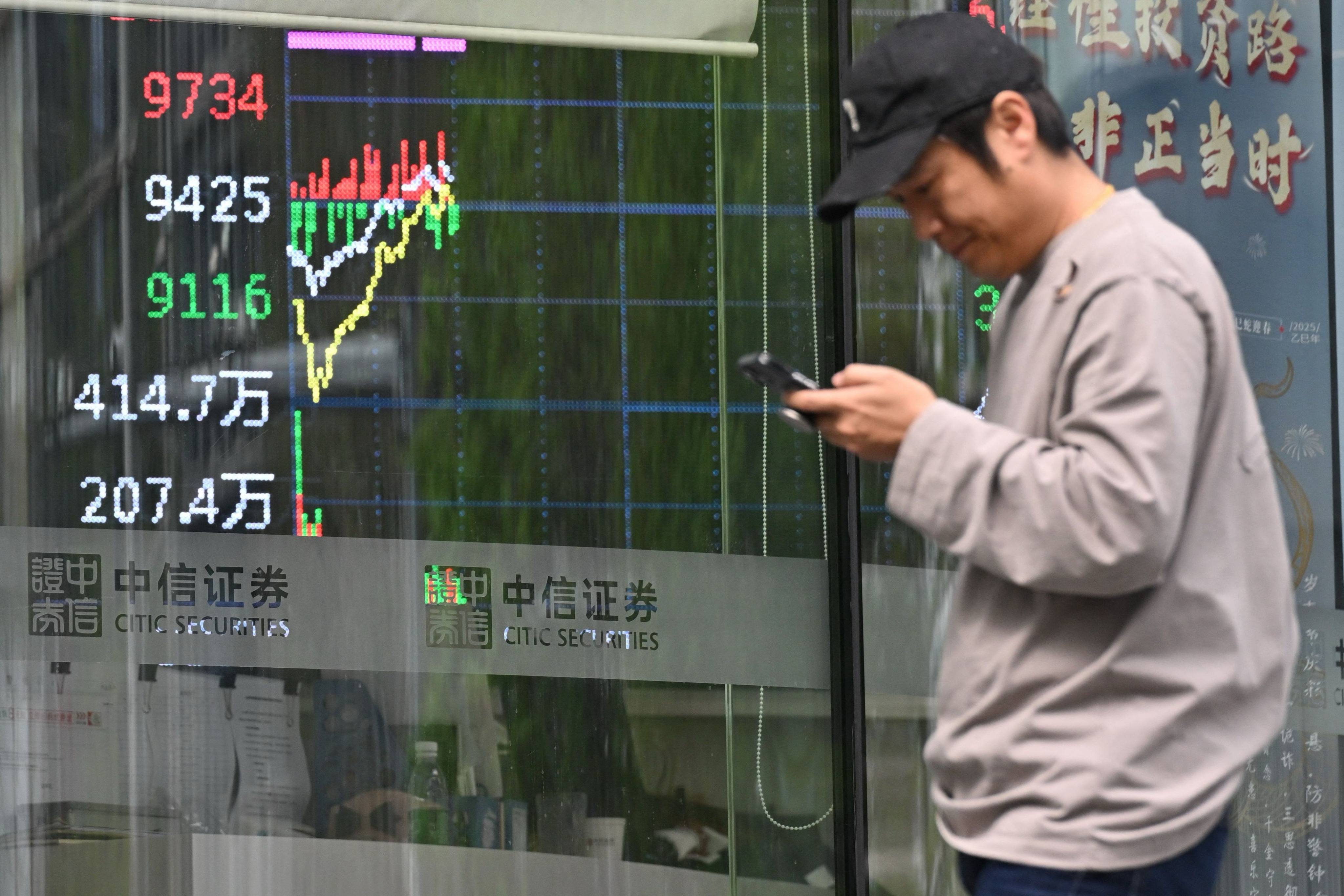 A man walks past a screen showing stock trading in Beijing on April 9, 2025. Photo: AFP