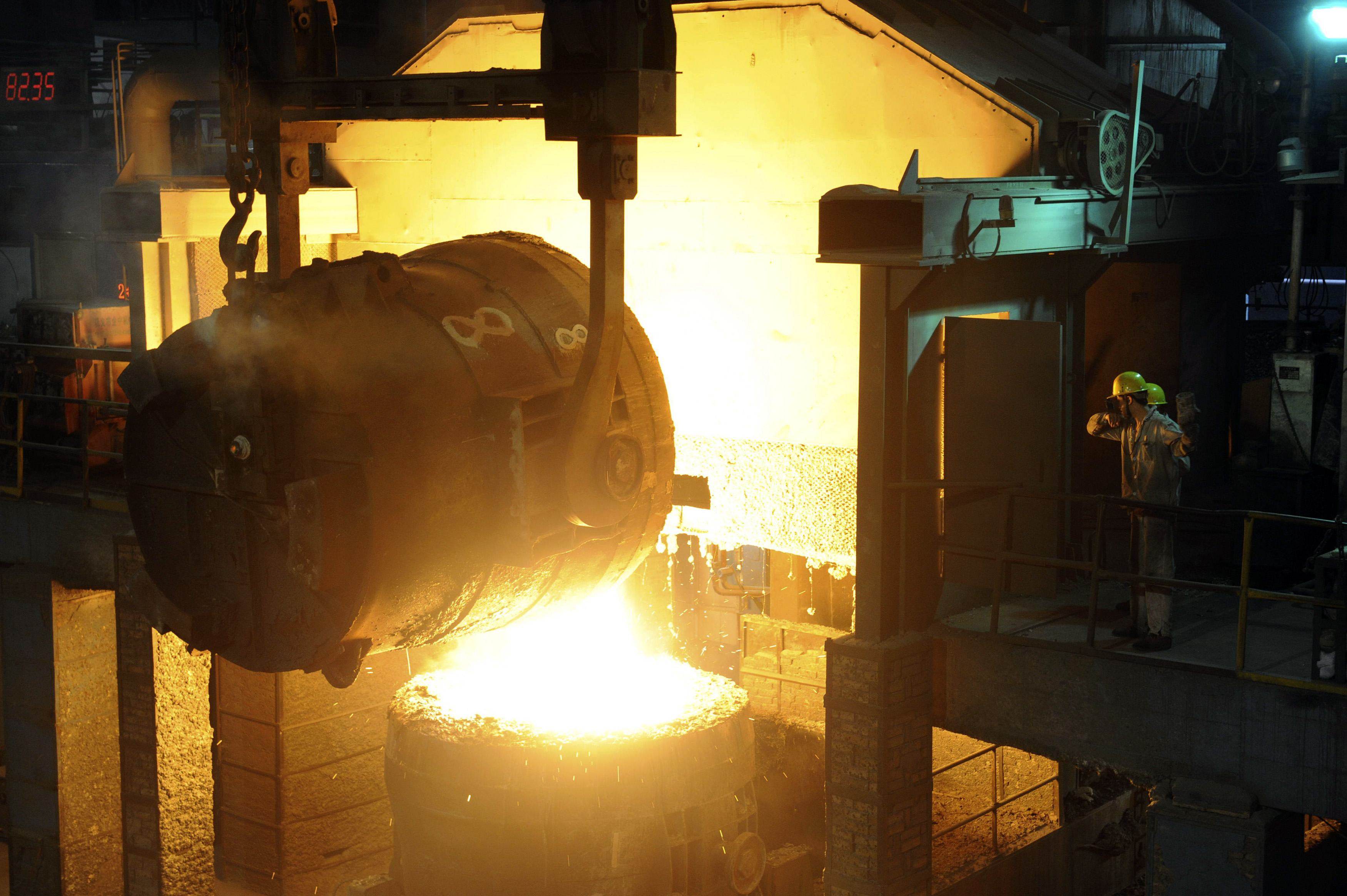 Workers look at a ladle pouring molten iron into a container at a steel plant in Hangzhou, eastern Zhejiang province. Photo: Reuters