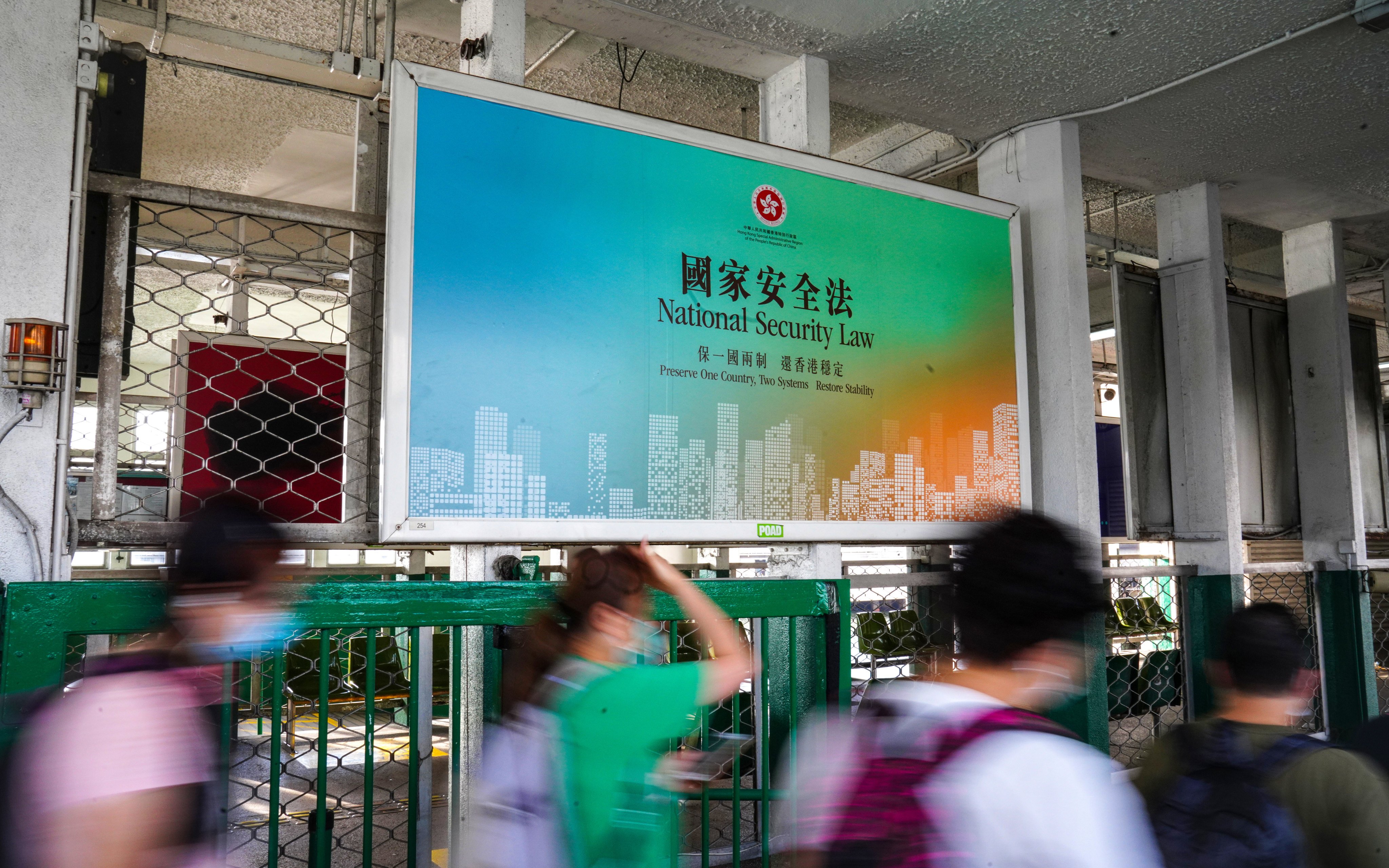 People walk past a large banner promoting the Hong Kong National Security Law at the Star Ferry Pier in Tsim Sha Tsui in June 2020. Photo: Sam Tsang