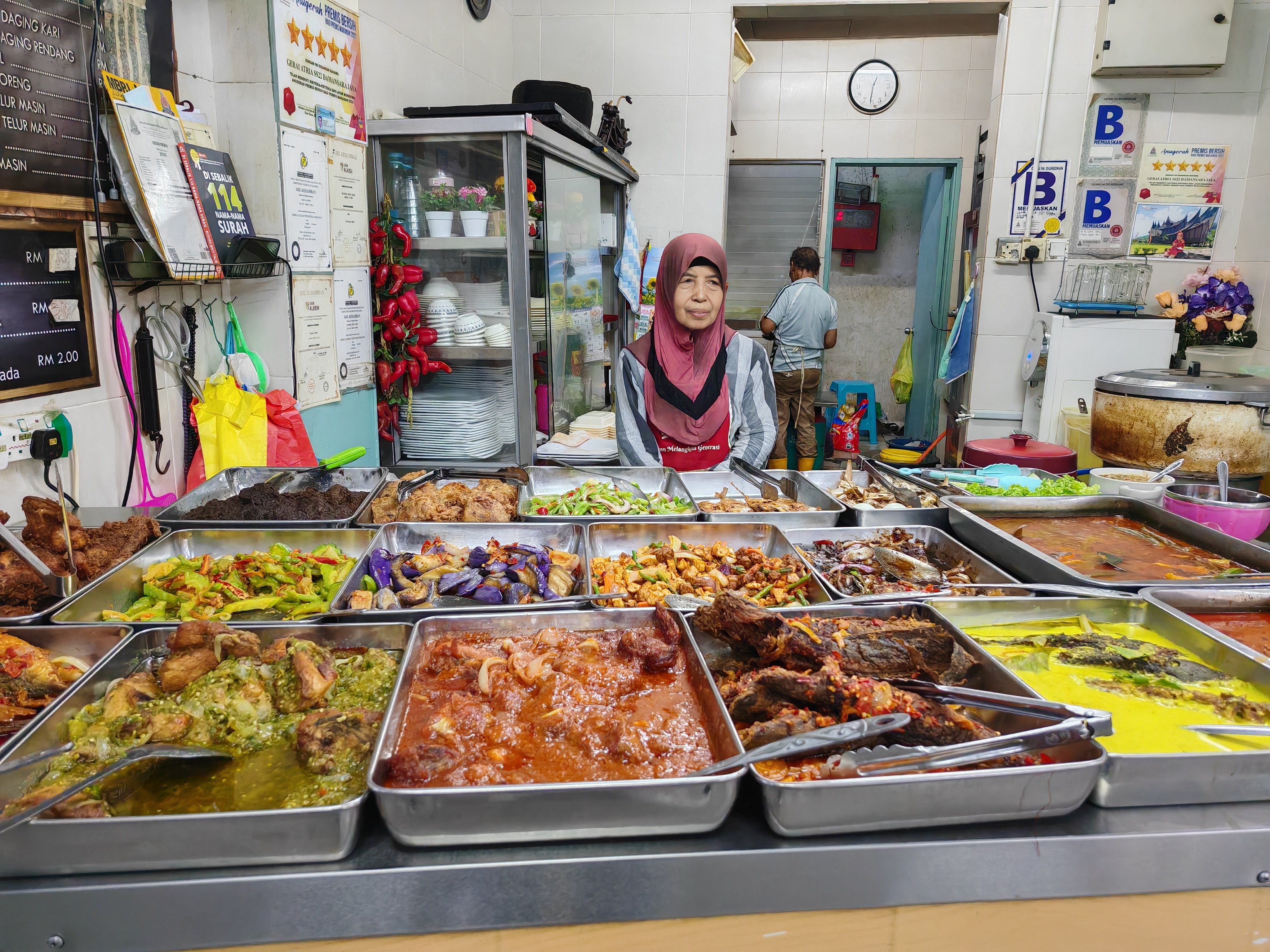 Rising cost of ingredients has forced Murni Adlis, 66, to raise the price of some of the dishes like beef rendang and fried chicken served at her nasi padang stall. Photo: Joseph Sipalan