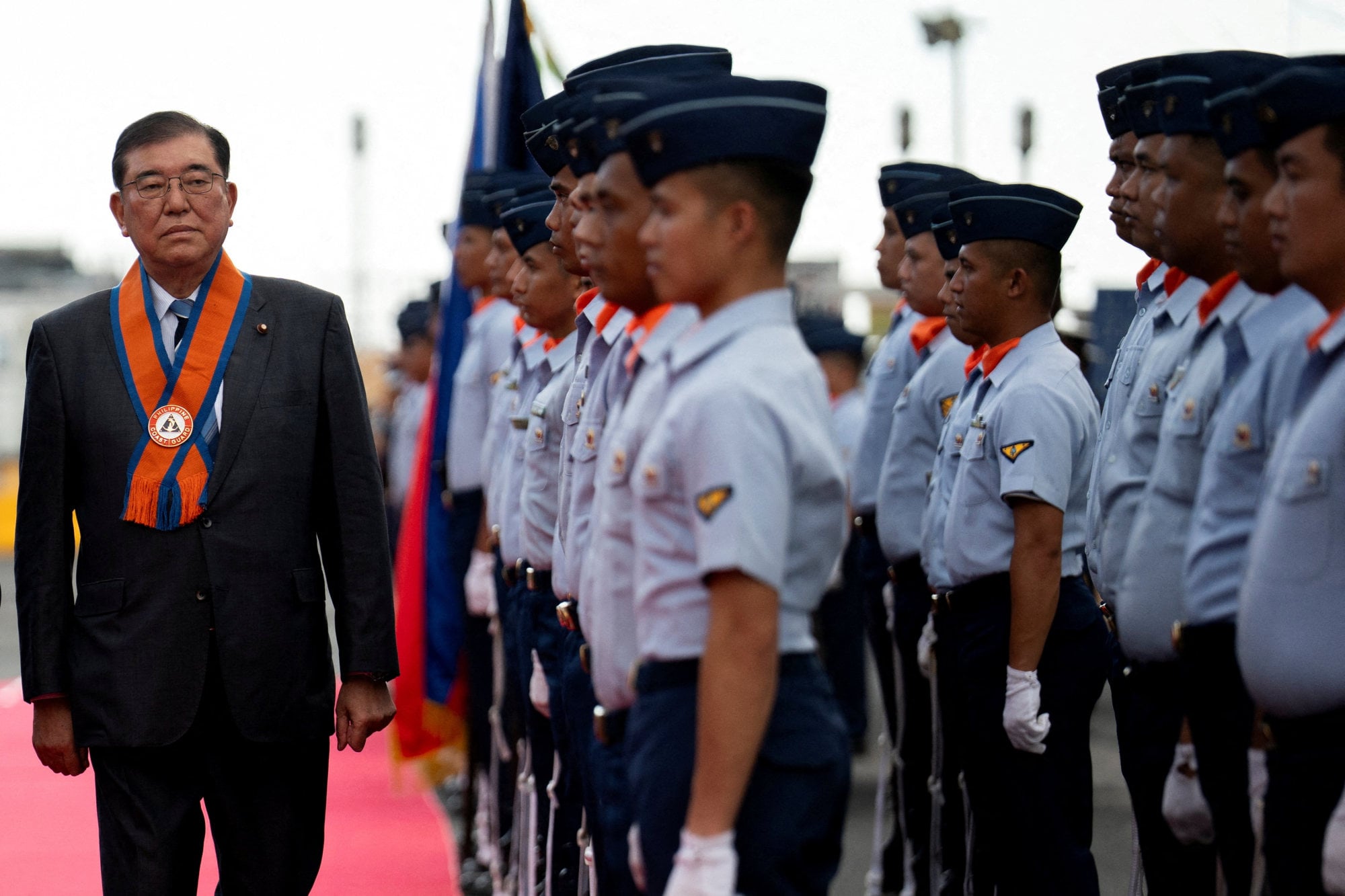 Japanese Prime Minister Shigeru Ishiba walks past members of the Philippine Coast Guard during a visit to Philippine Coast Guard headquarters in Manila on Wednesday. Photo: Reuters