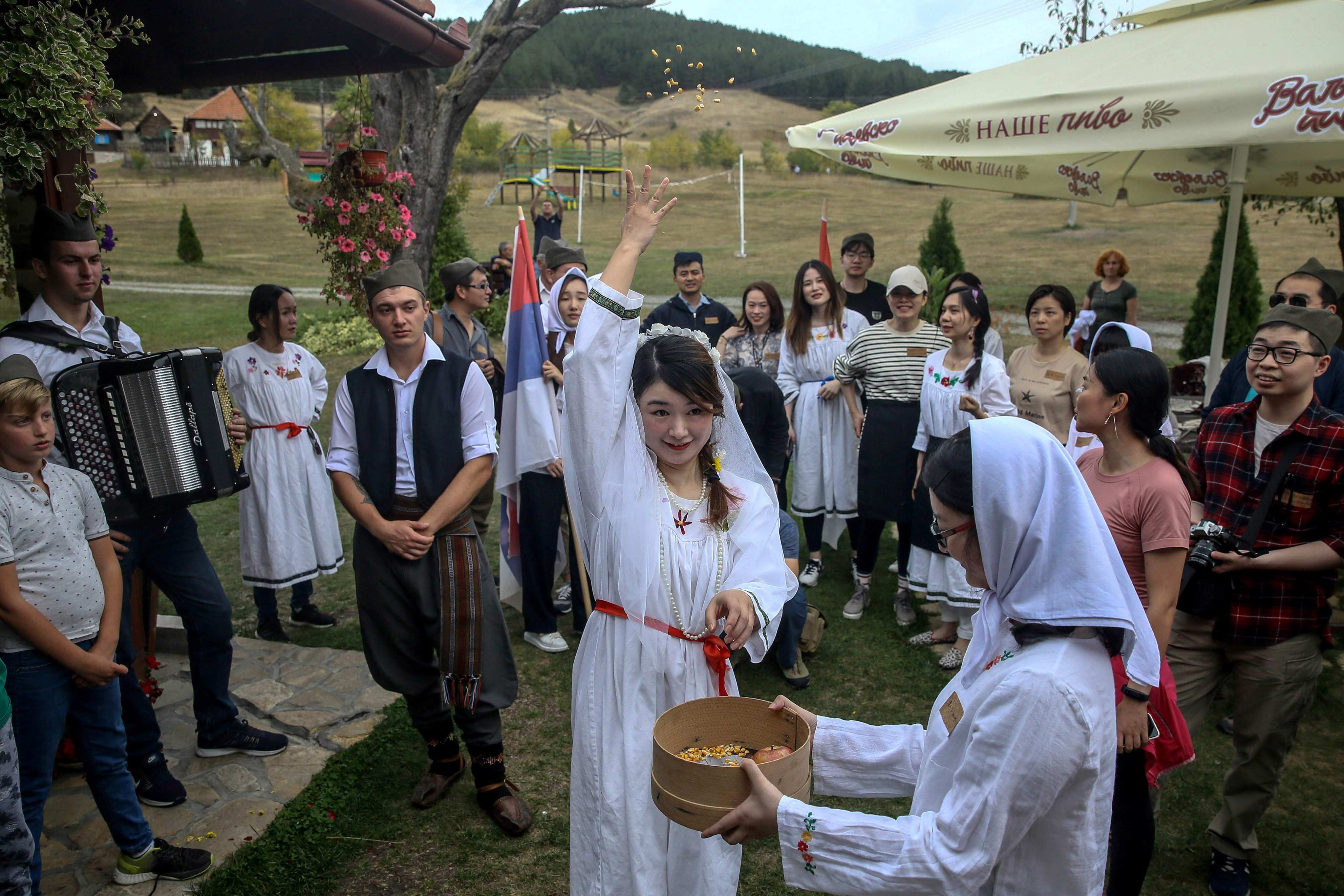A Chinese tourist throws wheat while dressed up as a bride for a traditional Serbian wedding experience in Gostoljublje, a village near the Serbian town of Kosjeric, in 2019. The year before the pandemic hit, Chinese tourists topped the world in outbound spending. Photo: AFP