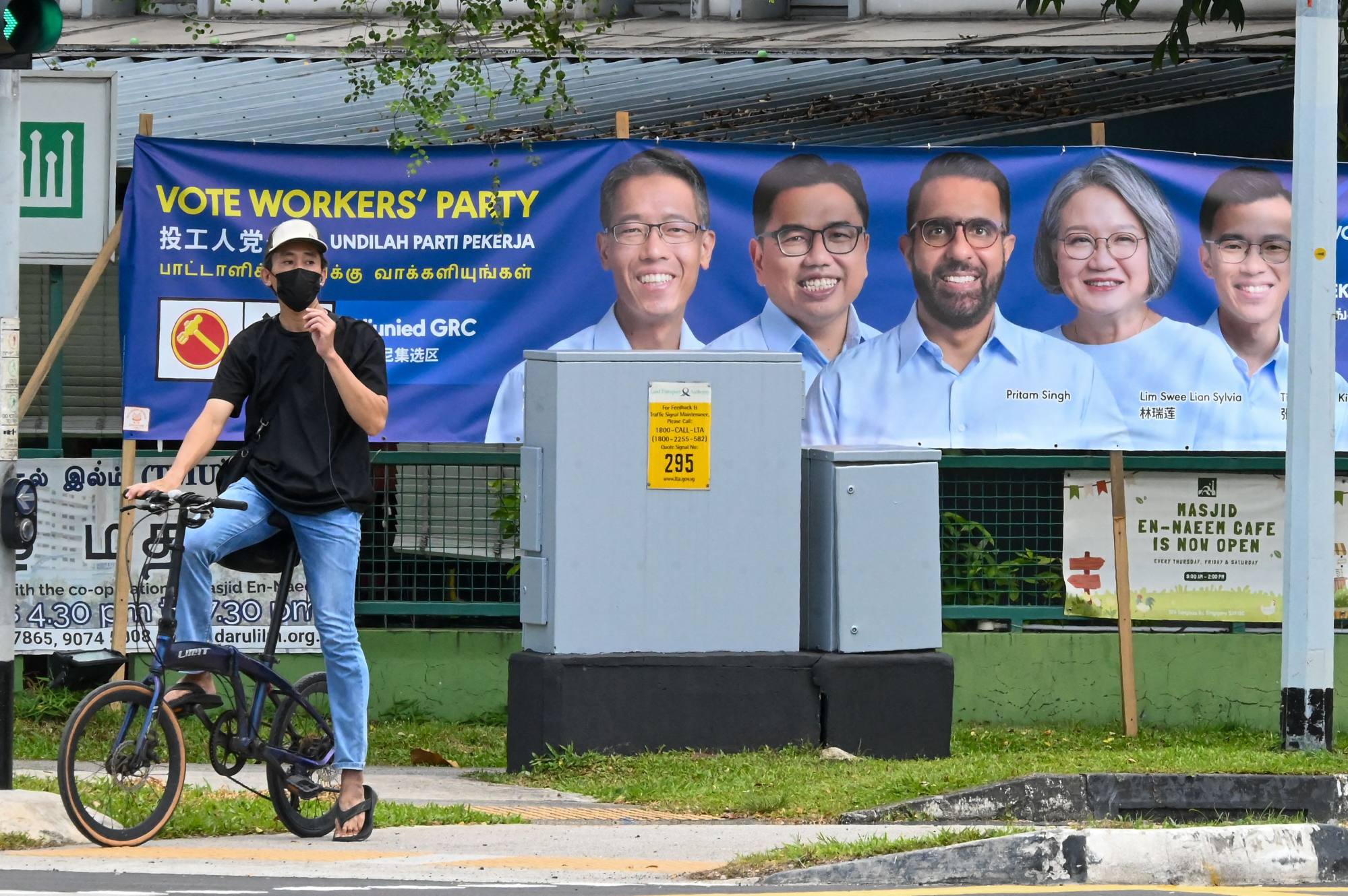 A cyclist waits to cross the road in front of election campaign posters for the opposition Workers’ Party leader Pritam Singh and his team in Singapore. Photo: AFP A cyclist waits to cross the road in front of election campaign posters for the opposition Workers’ Party leader Pritam Singh and his team in Singapore. Photo: AFP