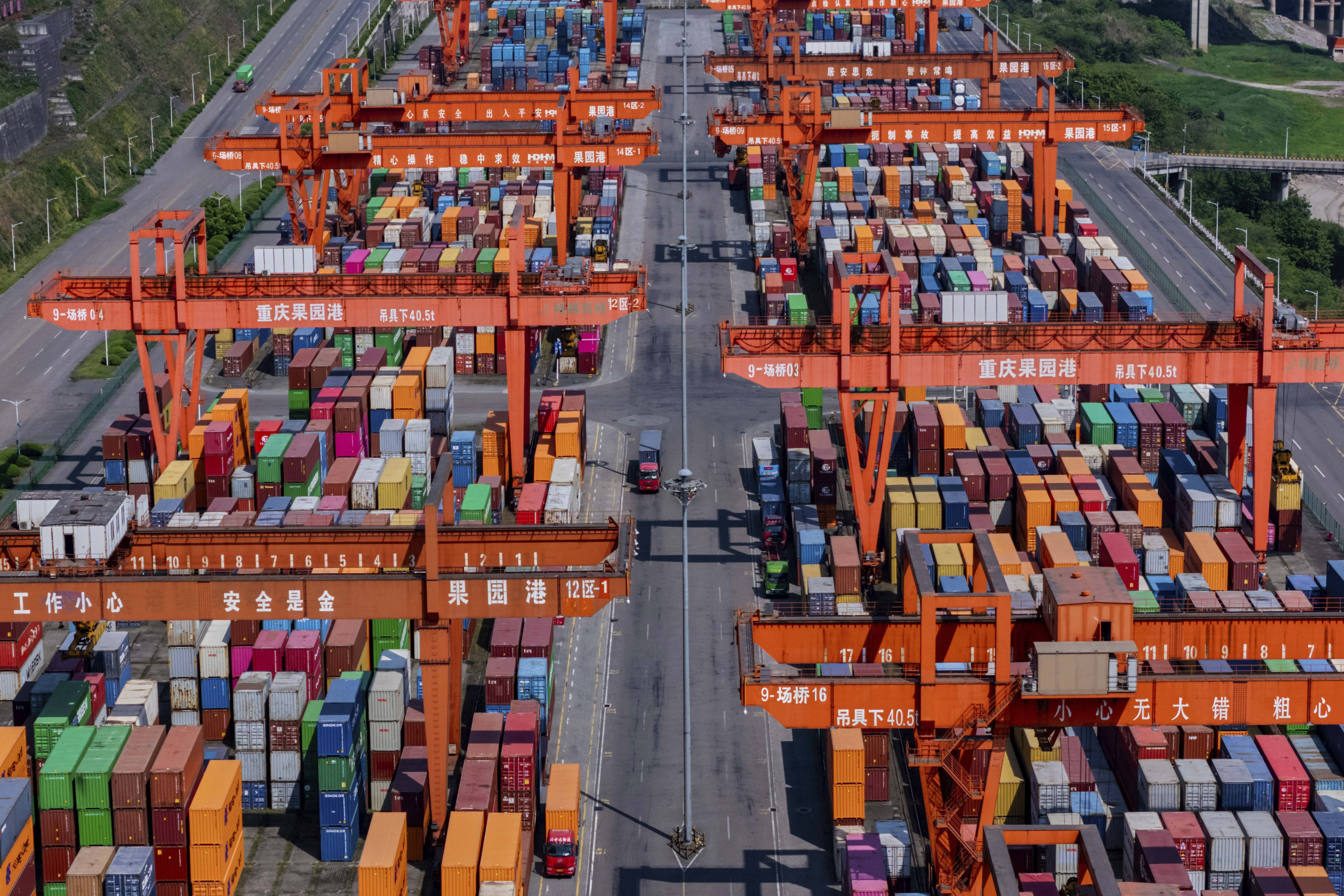 Trucks move past piles of containers stacked at a container terminal port on the Yangtze River in southwest China’s Chongqing Municipality on April 20. Photo: AP