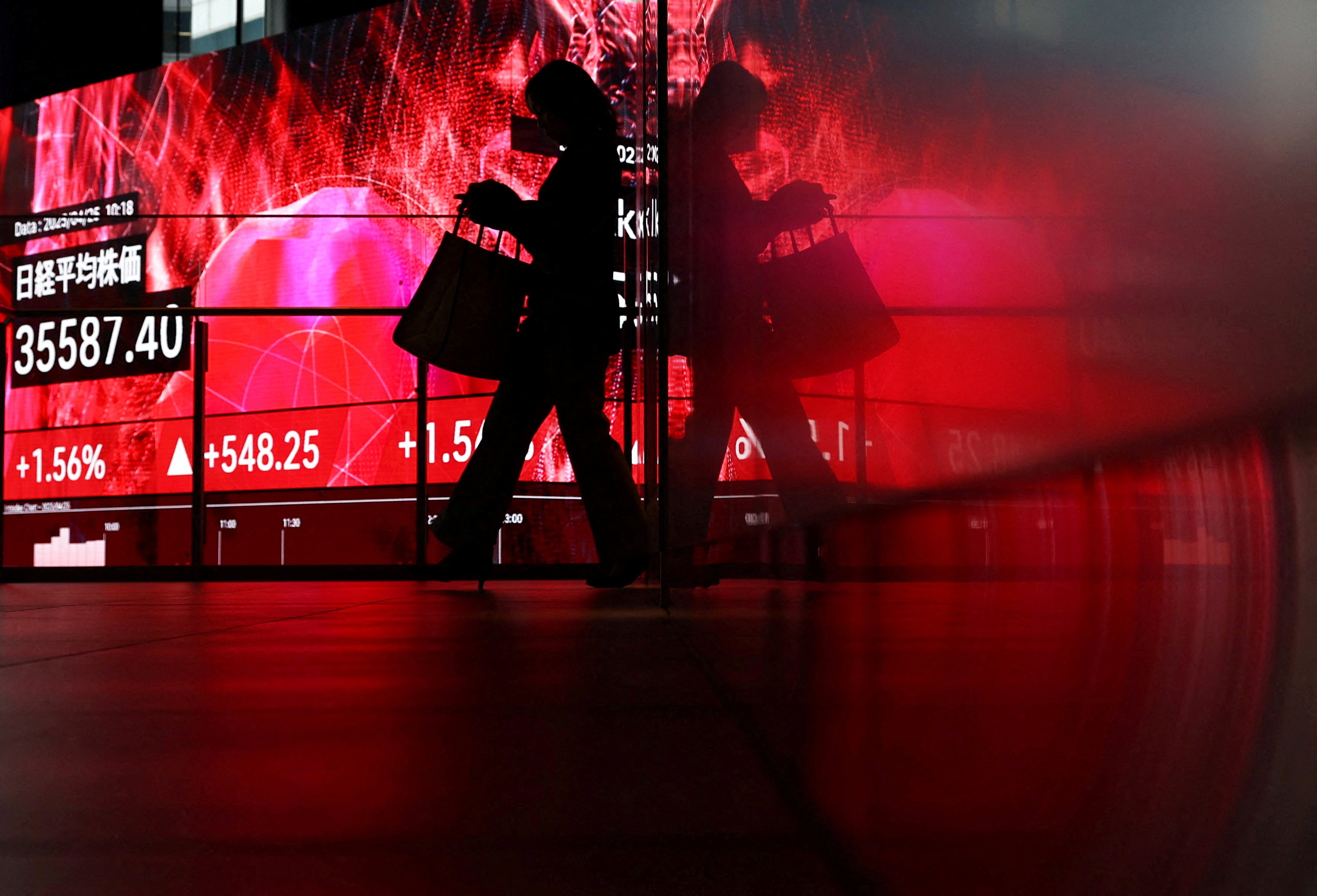 A woman walks in front of a screen displaying Japan’s Nikkei share average inside a building in Tokyo, Japan, on Friday. US tariffs have hit the country’s economy hard. Photo: Reuters