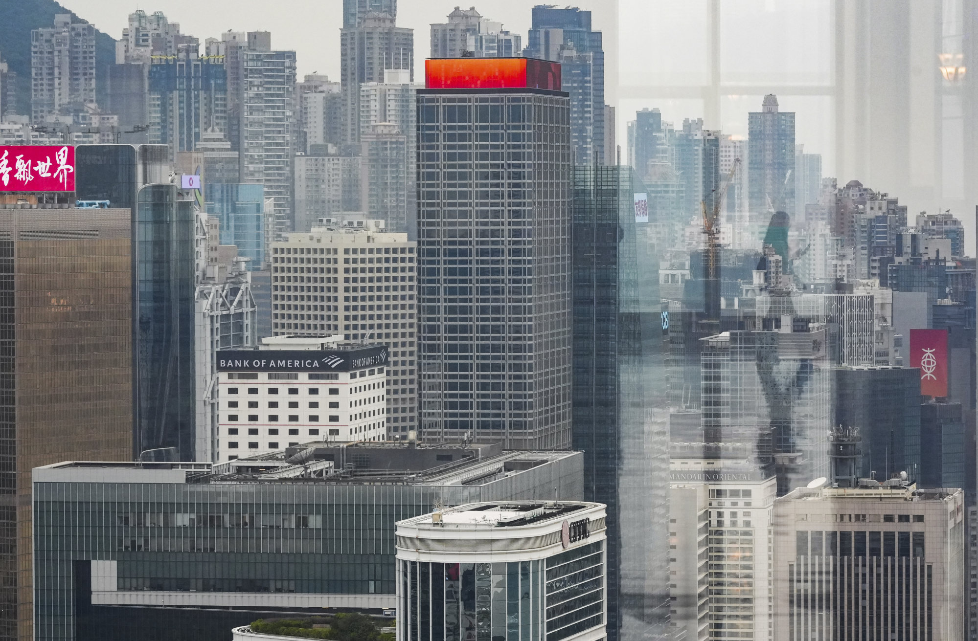Glass reflects a woman silhouette among commercial buildings on Hong Kong Island on February 26, 2025. Photo: Eugene Lee